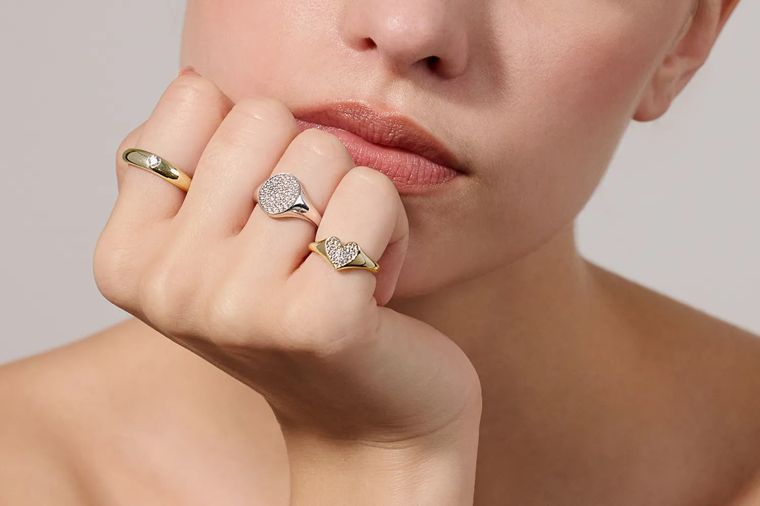 Frau trägt drei Ringe aus Silber mit Steinbesatz von Mabina Gioielli - ein goldener Ring, ein silberner Ring und ein goldener Ring in Herzform
