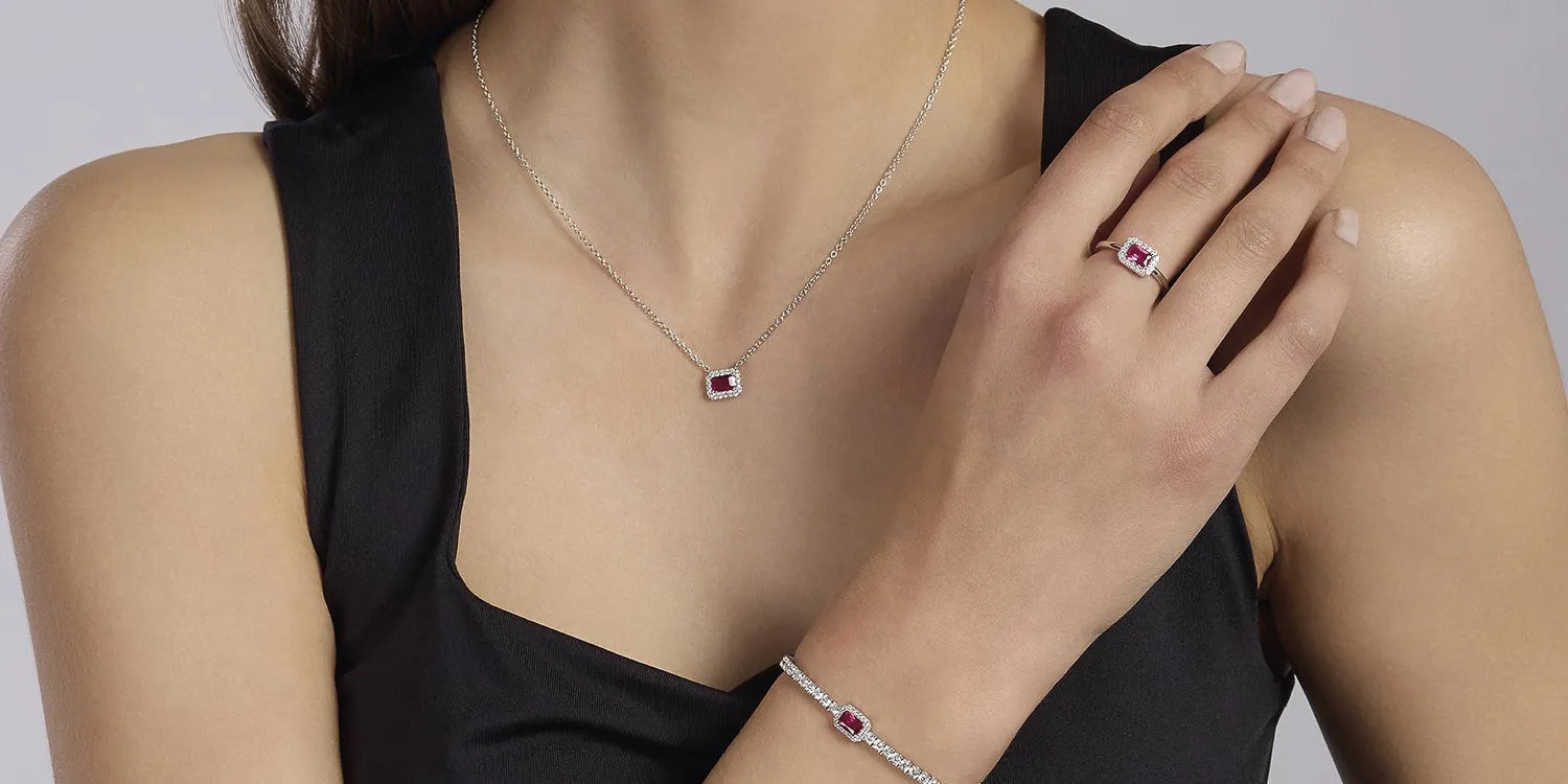 Frau trägt ein silbernes Schmuckset von Mabina mit roten rechteckigen Ziersteinen und Zirkonia-Besatz, bestehend aus Armband, Ring und Collier