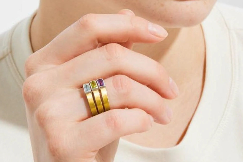 Frau präsentiert den selben Manu Ring in drei Edelstein-Varianten an Ihrem Finger