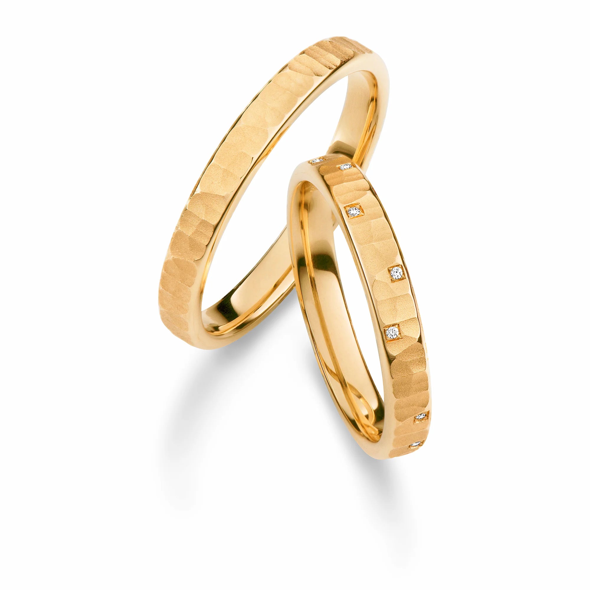 Produktfotografie des gelbgoldenen Max Kemper Trauringpaars mir gehämmerter Oberflächenstruktur und mit kleinen zufällig platzierten Diamanten als Verzierung des Damenrings