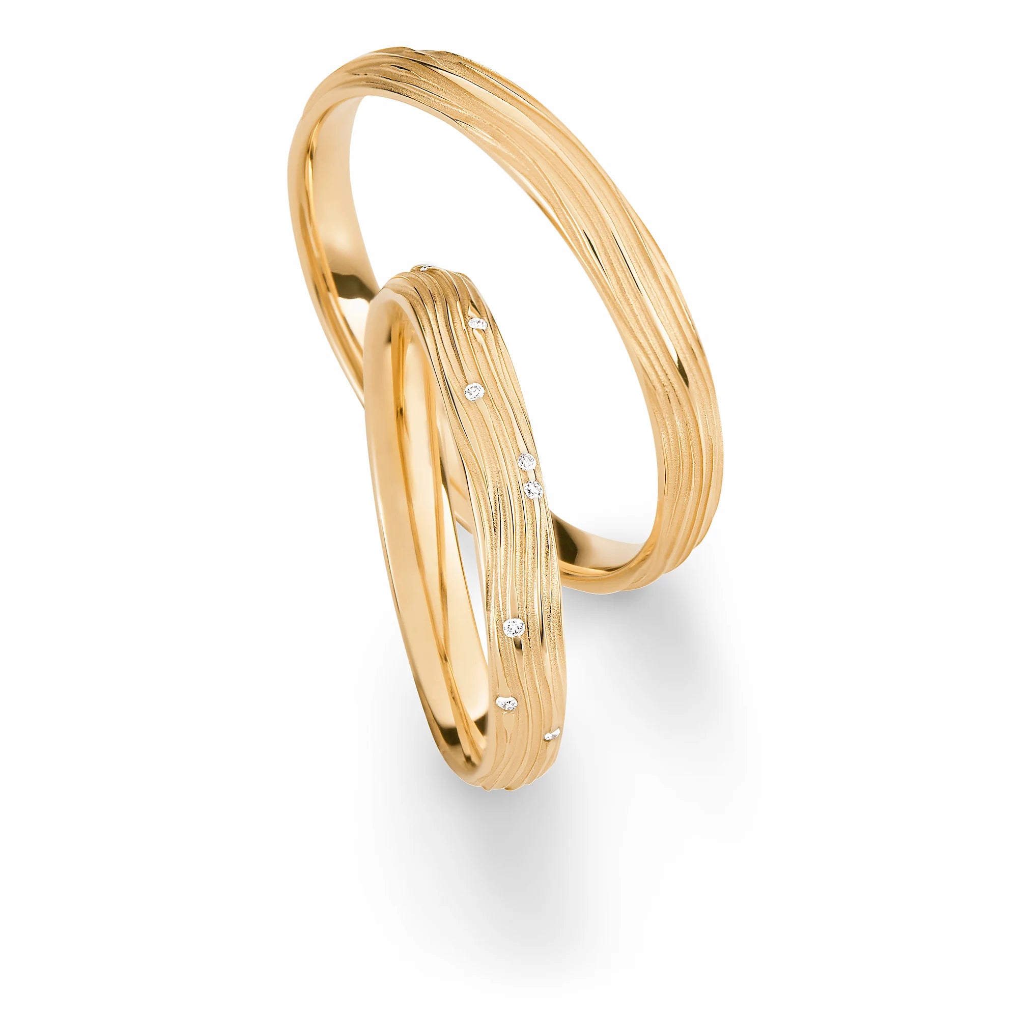 Produktfotografie des gelbgoldenen Max Kemper Trauringpaars mit organisch fließen Linien als Oberflächen-Verzierung und Diamanten im Damenring