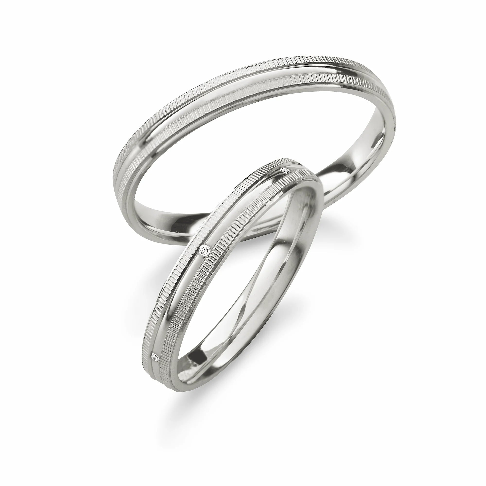 Produktfotografie des weißgoldenen Max Kemper Trauringpaars mit einer besonderen Form der Ringschiene mit einer Kannelierung an den Außenkanten und speziell für den Damenring eingefassten Diamanten