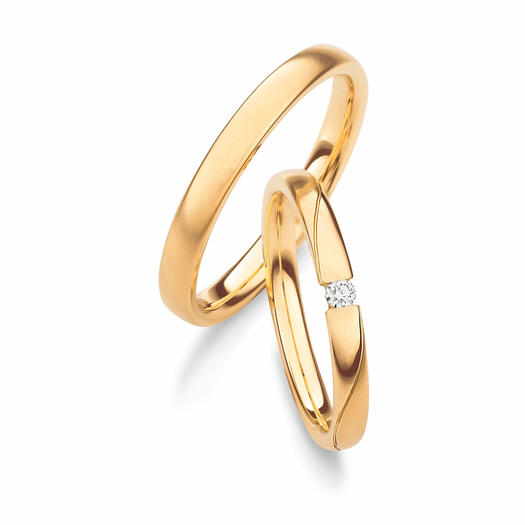 Produktfotografie des gelbgoldenen Max Kemper Trauringpaars mit einer feinen Oberflächenstruktur und einer wellenförmigen Nut mit einem Diamanten im Damenring
