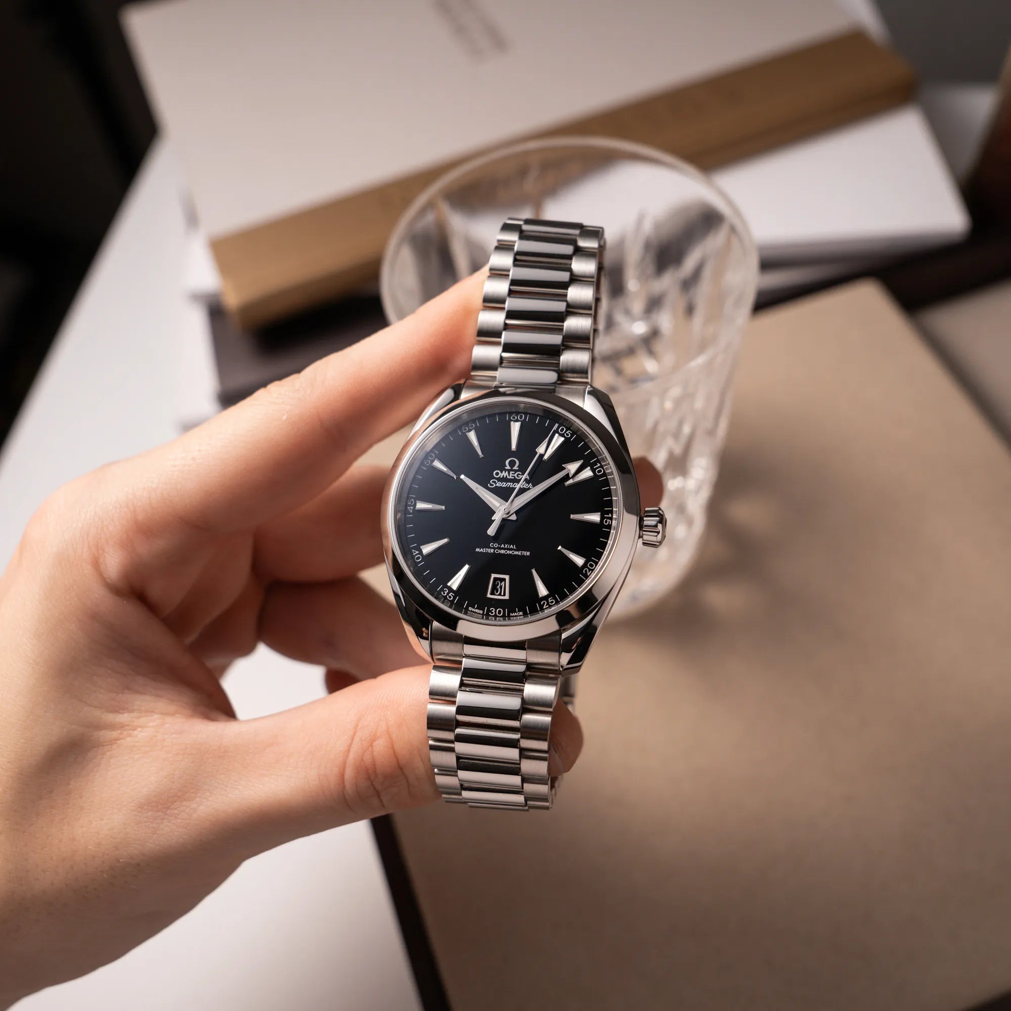 Mann hält die Omega Seamaster Aqua Terra Co-Axial der Referenz 220.10.41.21.01.002 mit schwarz lackiertem Zifferblatt in seiner Hand und präsentiert die Uhr in die Kamera