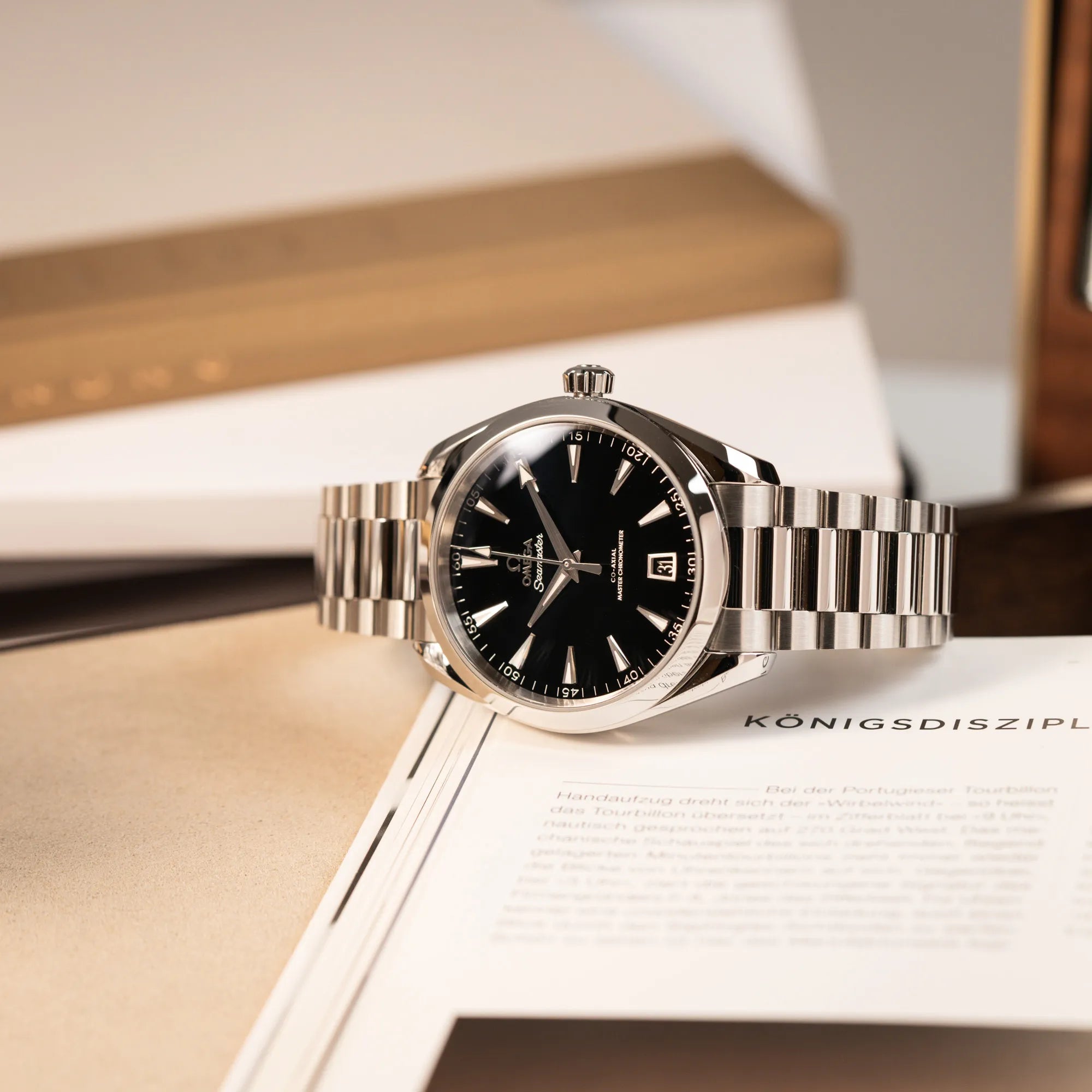 Produktfotografie der Omega Seamaster Aqua Terra Co-Axial der Referenz 220.10.41.21.01.002 mit schwarz lackiertem Zifferblatt, während die Uhr auf einem Uhrenbuch