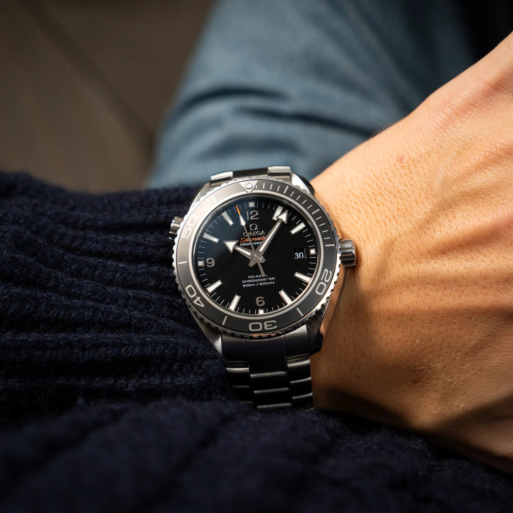 Mann trägt die Omega Seamaster Planet Ocean 232.30.46.21.01.001 mit 45mm Gehäuse und schwarzem Zifferblatt mit orangen Details an seinem Handgelenk