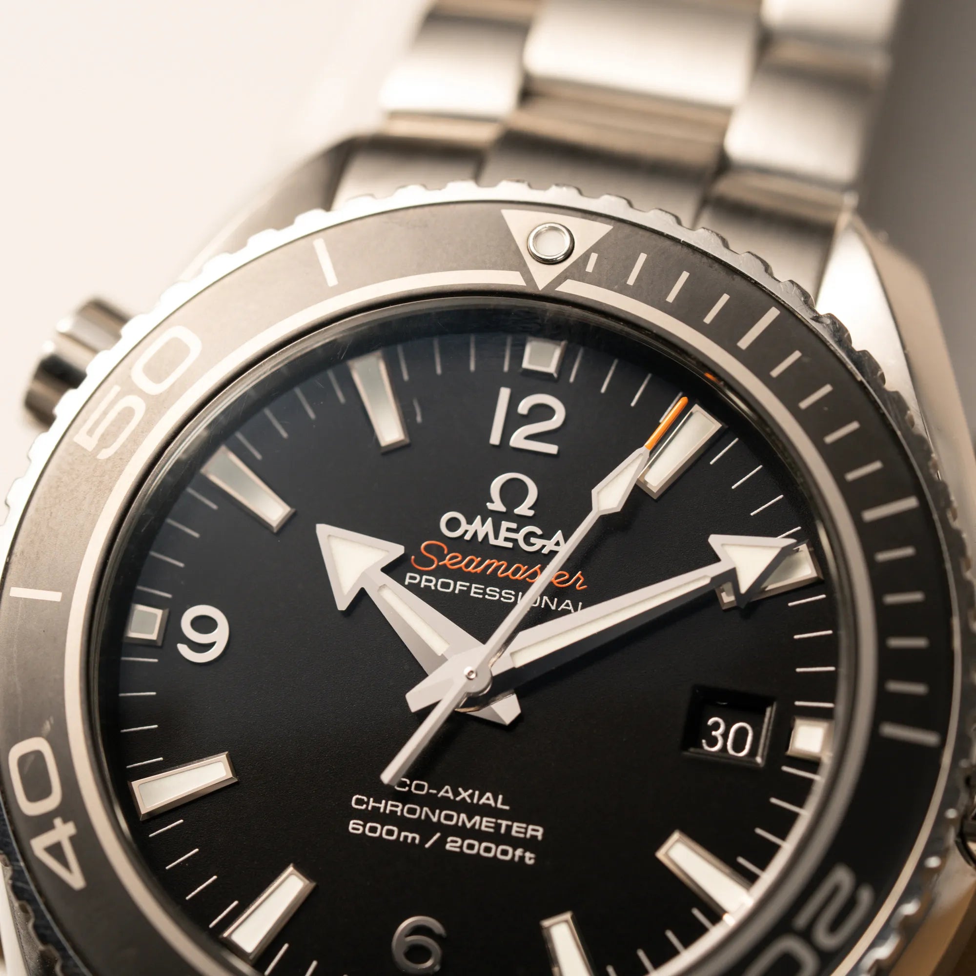 Makroaufnahme der Omega Seamaster Planet Ocean 232.30.46.21.01.001 mit 45mm Gehäuse mit Fokus auf dem schwarzem Zifferblatt mit orangen Details