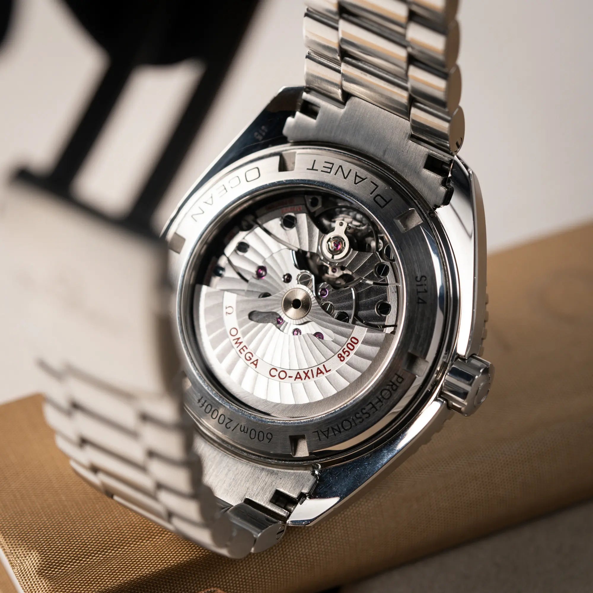 Produktfotografie zeigt den Gehäuseboden mit Sichtglas der Omega Seamaster Planet Ocean 232.30.46.21.01.001 mit 45mm Gehäuse und schwarzem Zifferblatt mit orangen Details