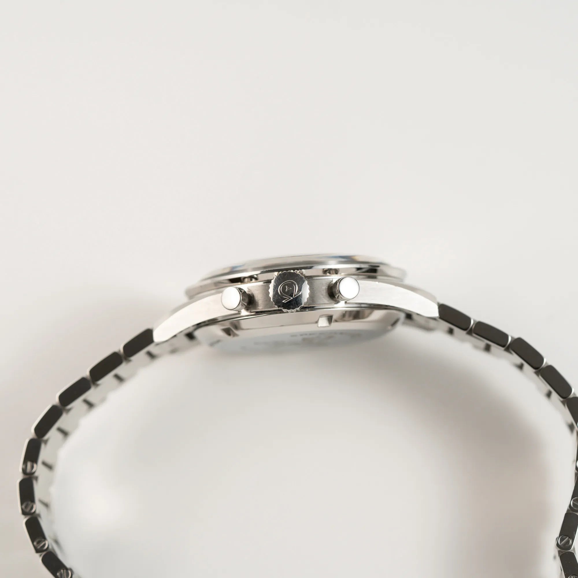 Seitliche Gehäuseflanke der Omega Speedmaster 1957 Trilogy Limited Edition mit einem anthrazitfarbenen Zifferblatt mit Vintage-Look und dem original Omega-Stahlband im Ed-White-Design zeigt die Aufzugskrone und die Chrono-Pusher