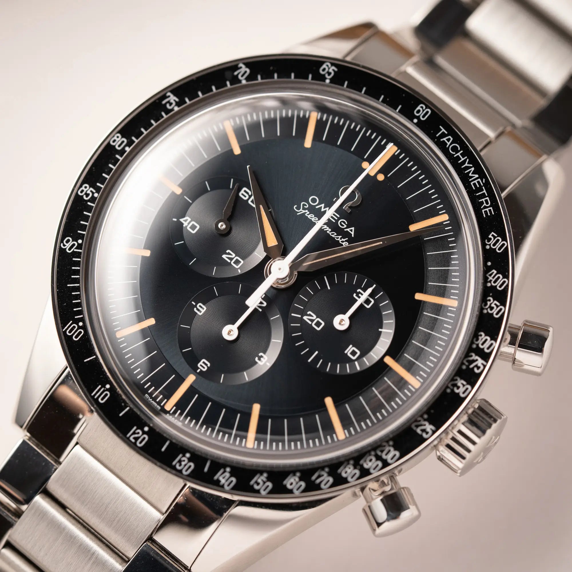 Uhrenkopf der Omega Speedmaster FOIS der Referenz 310.30.40.50.06.001 mit dem dunkelblauen Zifferblatt mit dunkel-beigen Indizes im Vintage-Look und einem vom Standard-Modell abgeänderten Stahl-Armband, was beides an das klassische Speedy-Modell erinnert