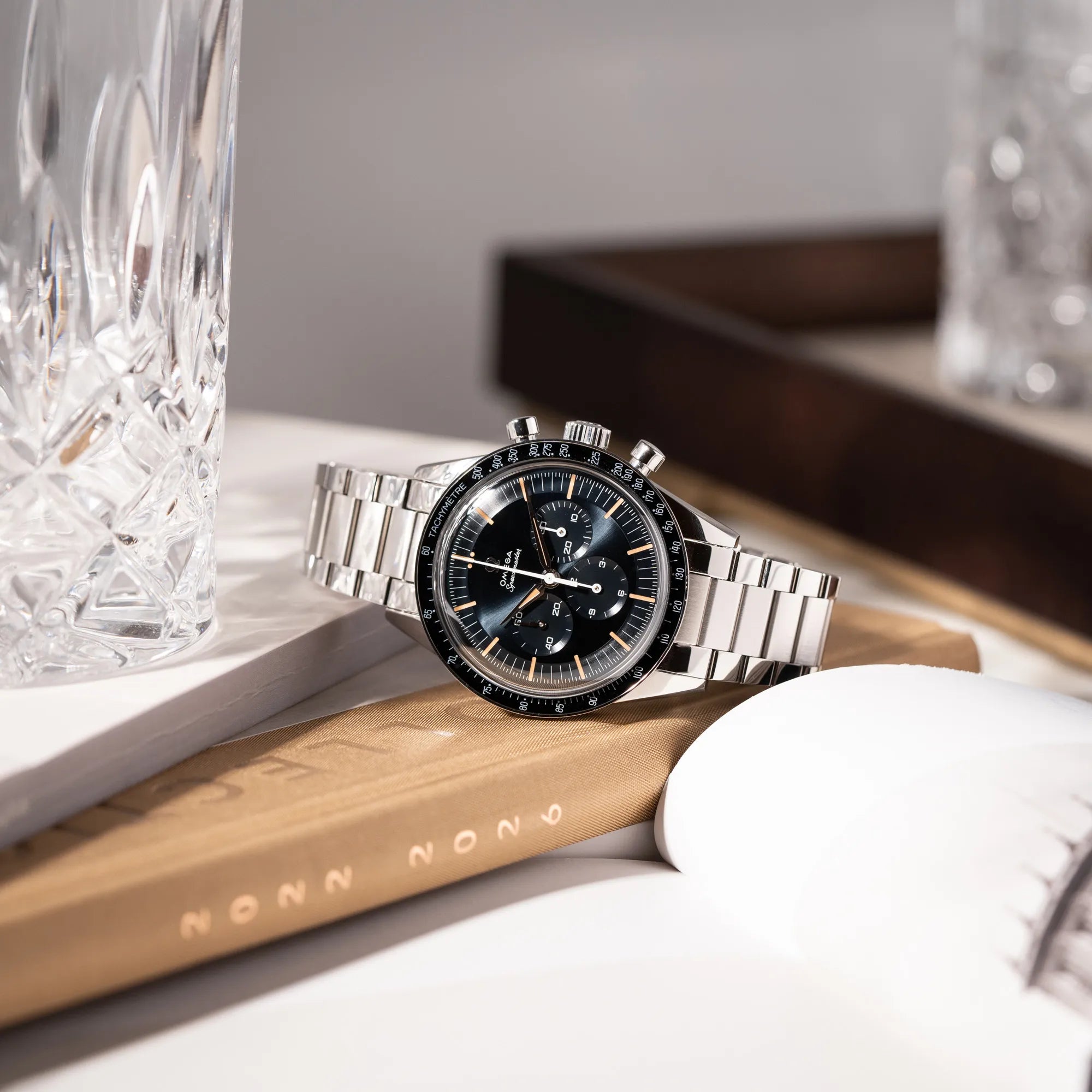 Produktfotografie der Omega Speedmaster FOIS der Referenz 310.30.40.50.06.001 mit dem dunkelblauen Zifferblatt mit dunkel-beigen Indizes im Vintage-Look und einem vom Standard-Modell abgeänderten Stahl-Armband, was beides an das klassische Speedy-Modell erinnert