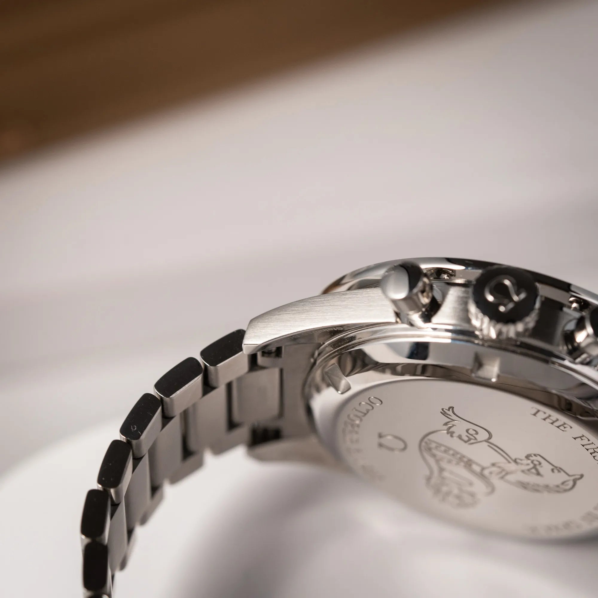 Detailaufnahme des rechten unteren Bandanstoßes der Omega Speedmaster FOIS der Referenz 310.30.40.50.06.001 mit dem dunkelblauen Zifferblatt mit dunkel-beigen Indizes im Vintage-Look und einem vom Standard-Modell abgeänderten Stahl-Armband, was beides an das klassische Speedy-Modell erinnert