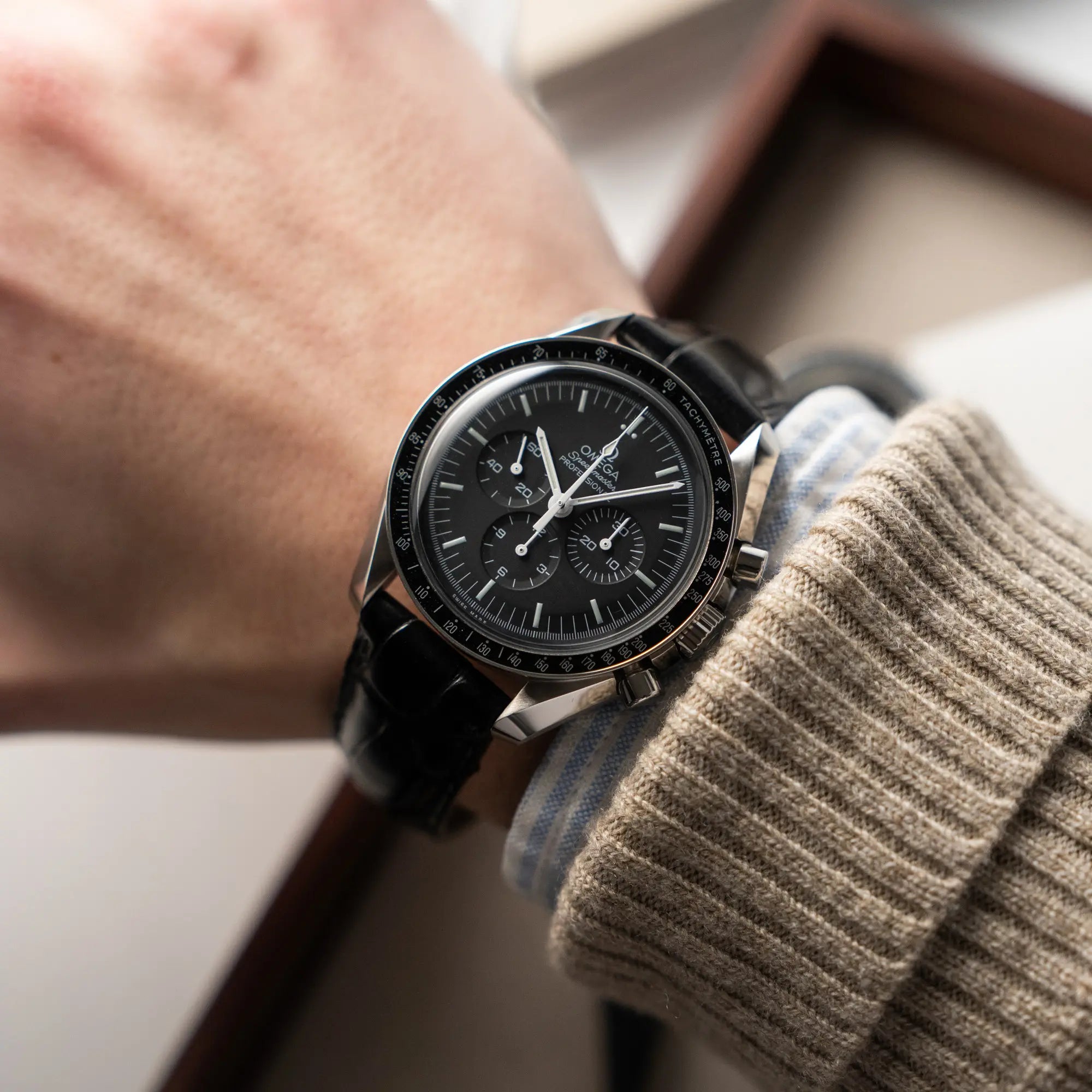 Mann trägt die Omega Speedmaster Moonwatch am schwarzen Lederband an seinem Handgelenk