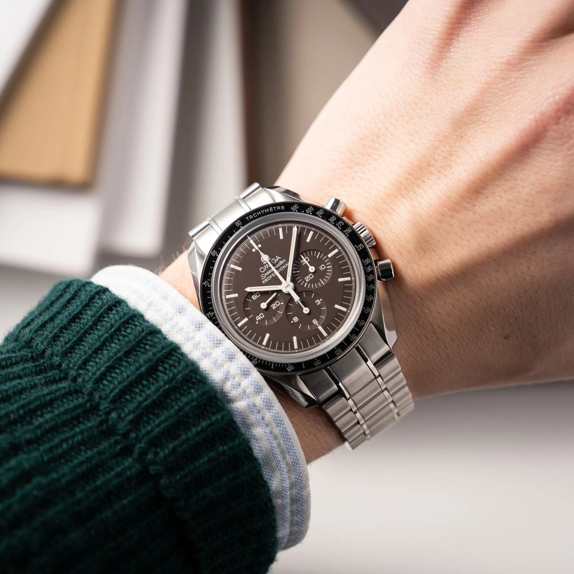 Mann trägt die Omega Speedmaster Professional Moonwatch 311.30.42.30.13.001 mit einem braunen Zifferblatt an seinem Handgelenk für einen Wristshot an seinem Handgelenk