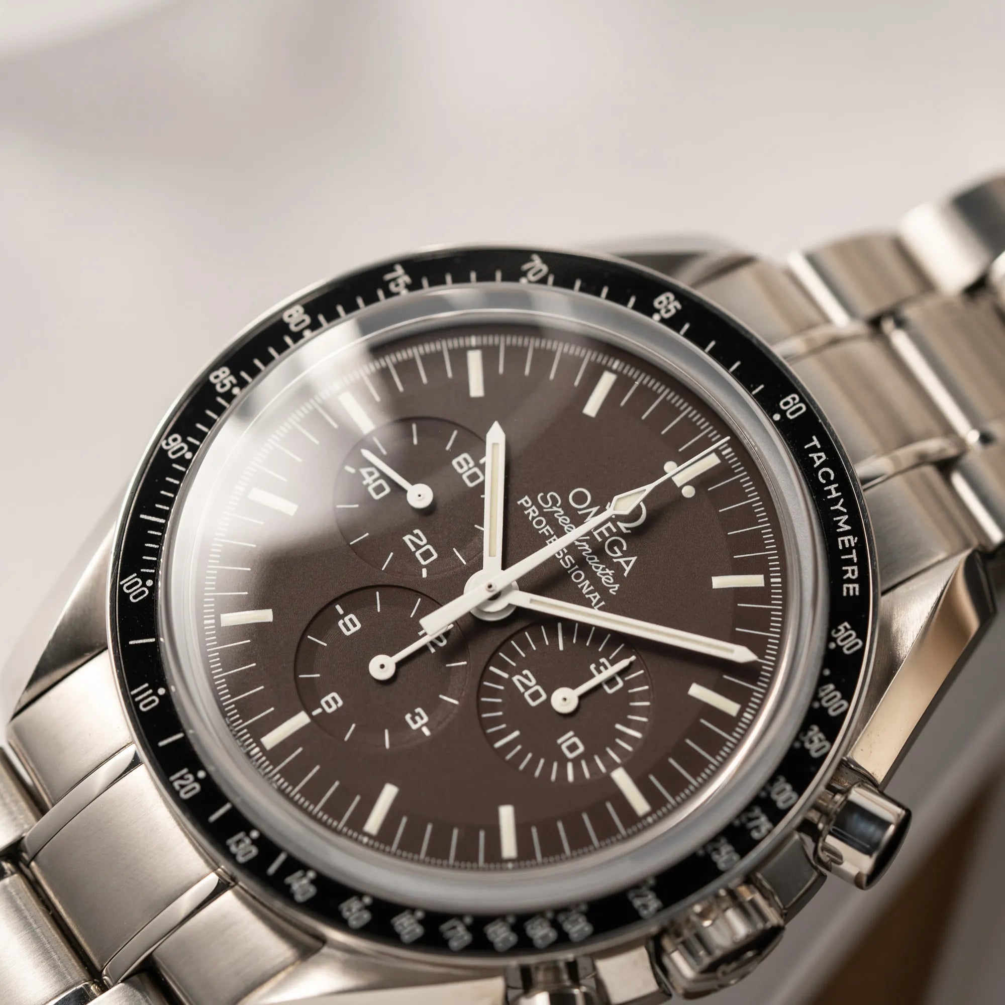 Detailaufnahme des Uhrenkopfes der Omega Speedmaster Professional Moonwatch 311.30.42.30.13.001 mit einem braunen Zifferblatt
