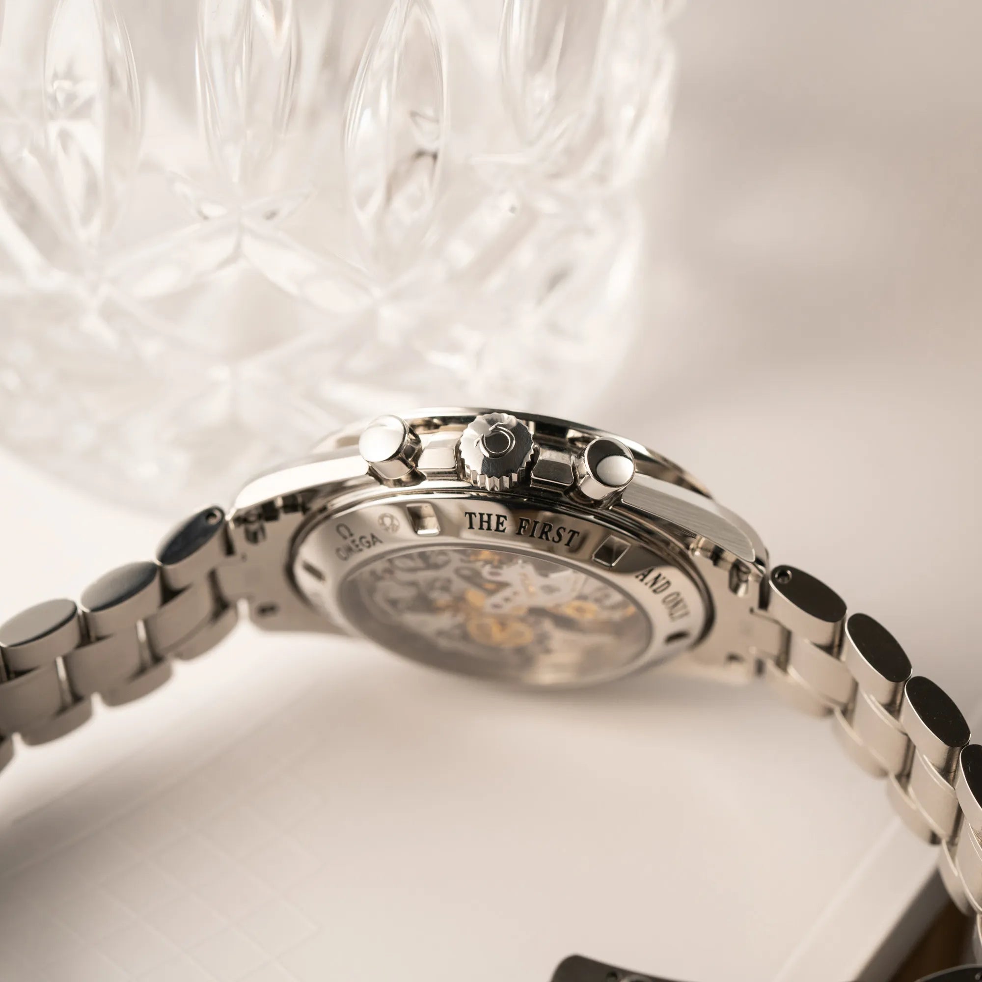 Produktfotografie der Omega Speedmaster Professional Moonwatch 311.30.42.30.13.001 mit einem braunen Zifferblatt zeigt dire Aufzugskrone und Chronograph-Pusher