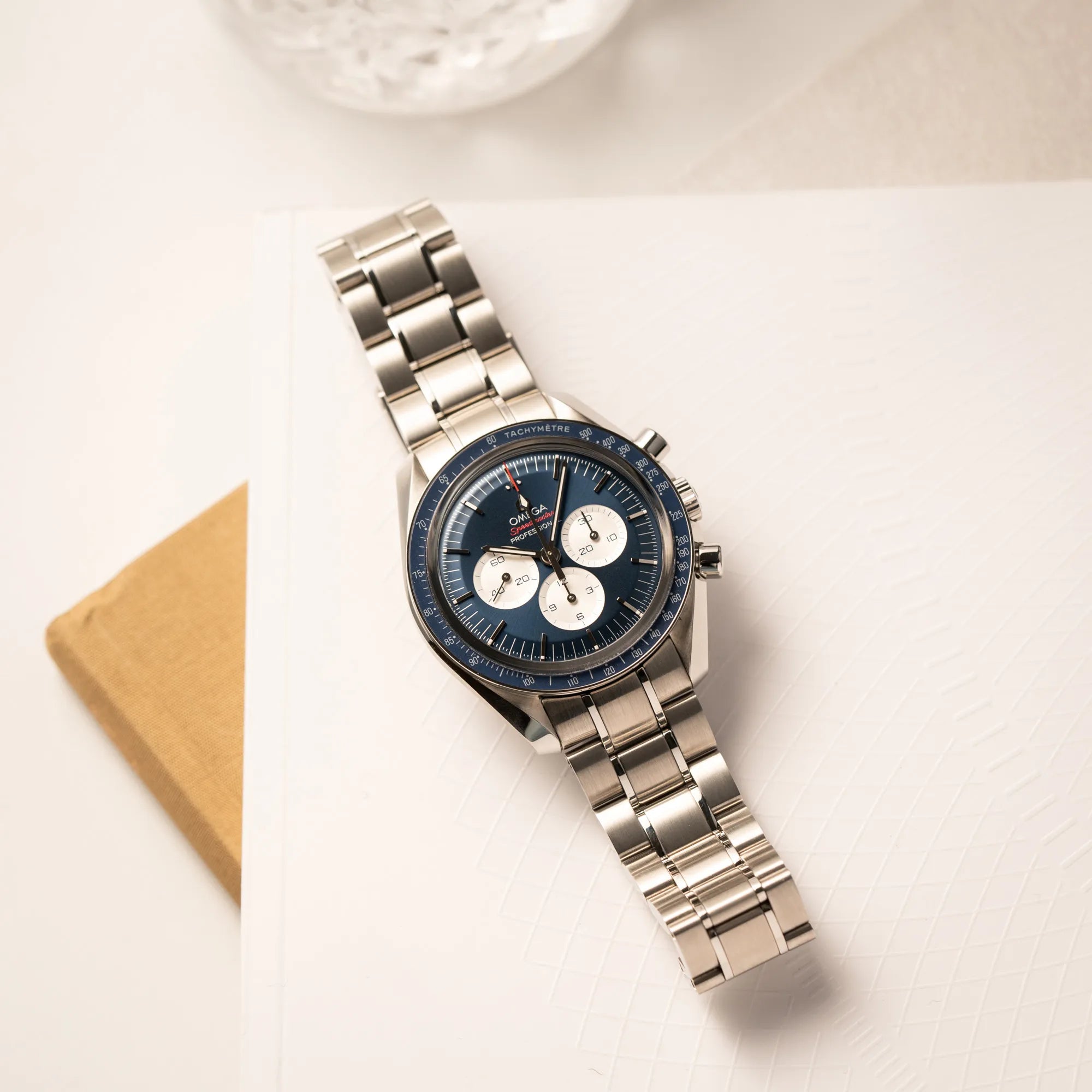 Produktfotografie der flach liegenden Omega Speedmaster Professional Moonwatch Tokyo Limited Edition mit blauem Zifferblatt und weißen Sub-Dials