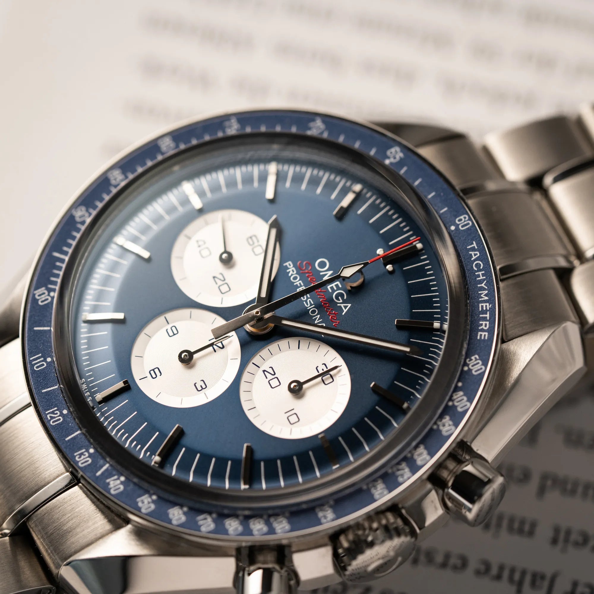 Detailaufnahme der Omega Speedmaster Professional Moonwatch Tokyo Limited Edition mit blauem Zifferblatt und weißen Sub-Dials mit Flus auf der Tachymetre Skala