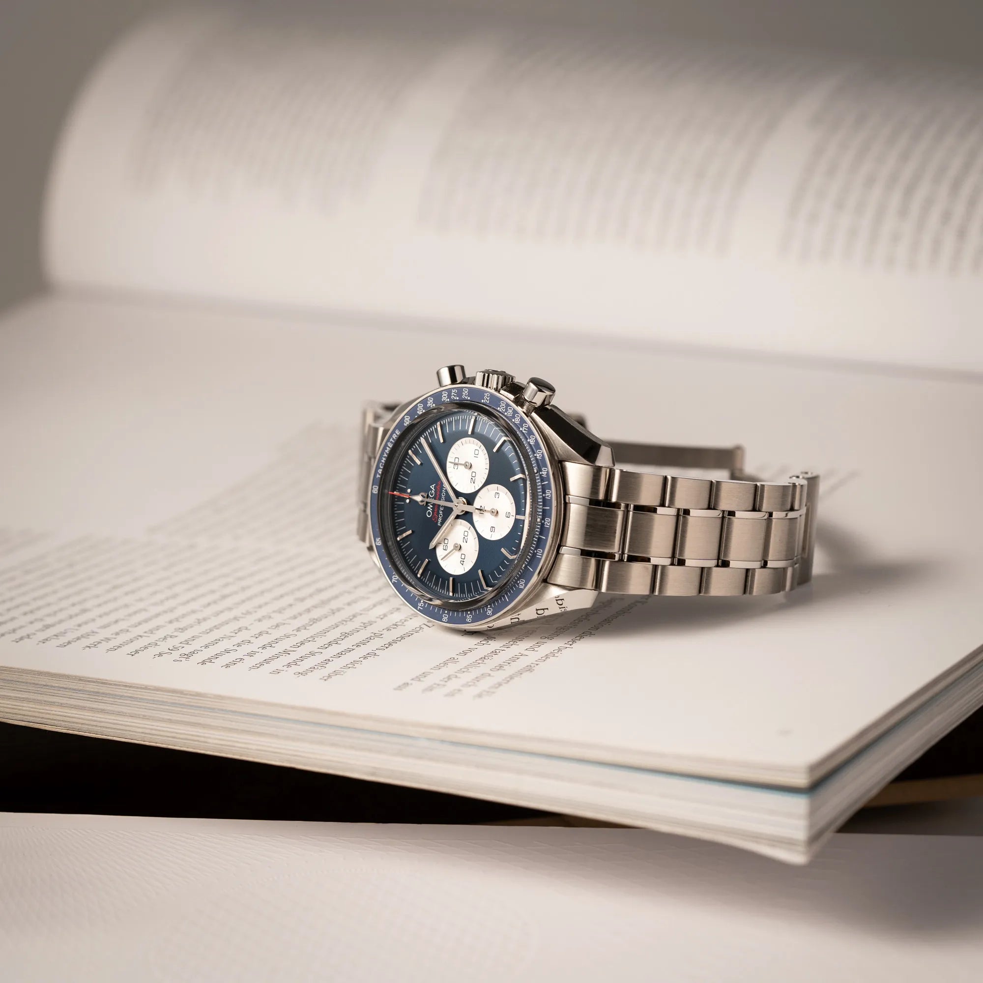Omega Speedmaster Professional Moonwatch Tokyo Limited Edition mit blauem Zifferblatt und weißen Sub-Dials liegt auf einem Buch
