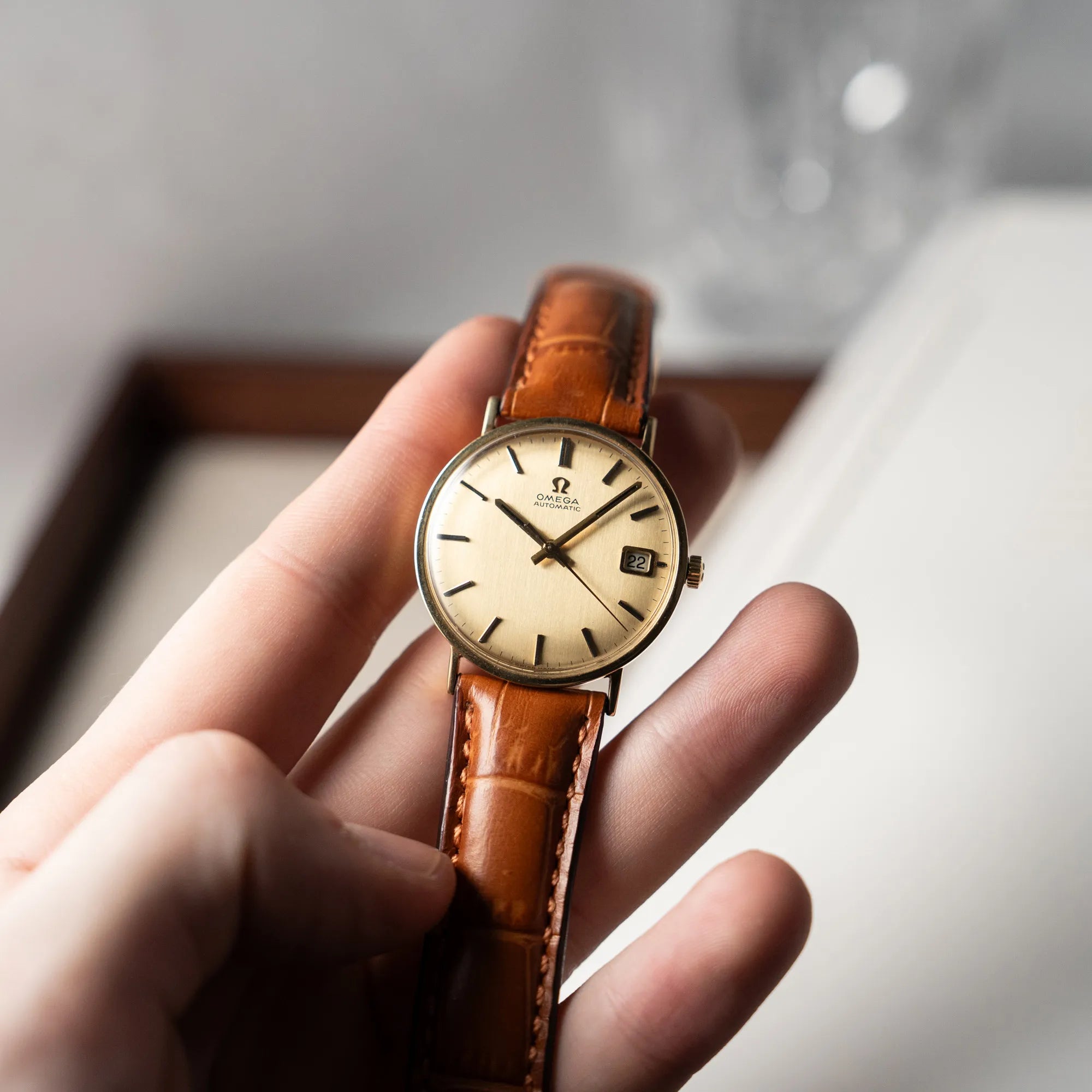 Mann hält die Omega Vintage Automatik Armbanduhr mit Gelbgold-Gehäuse in seiner Hand