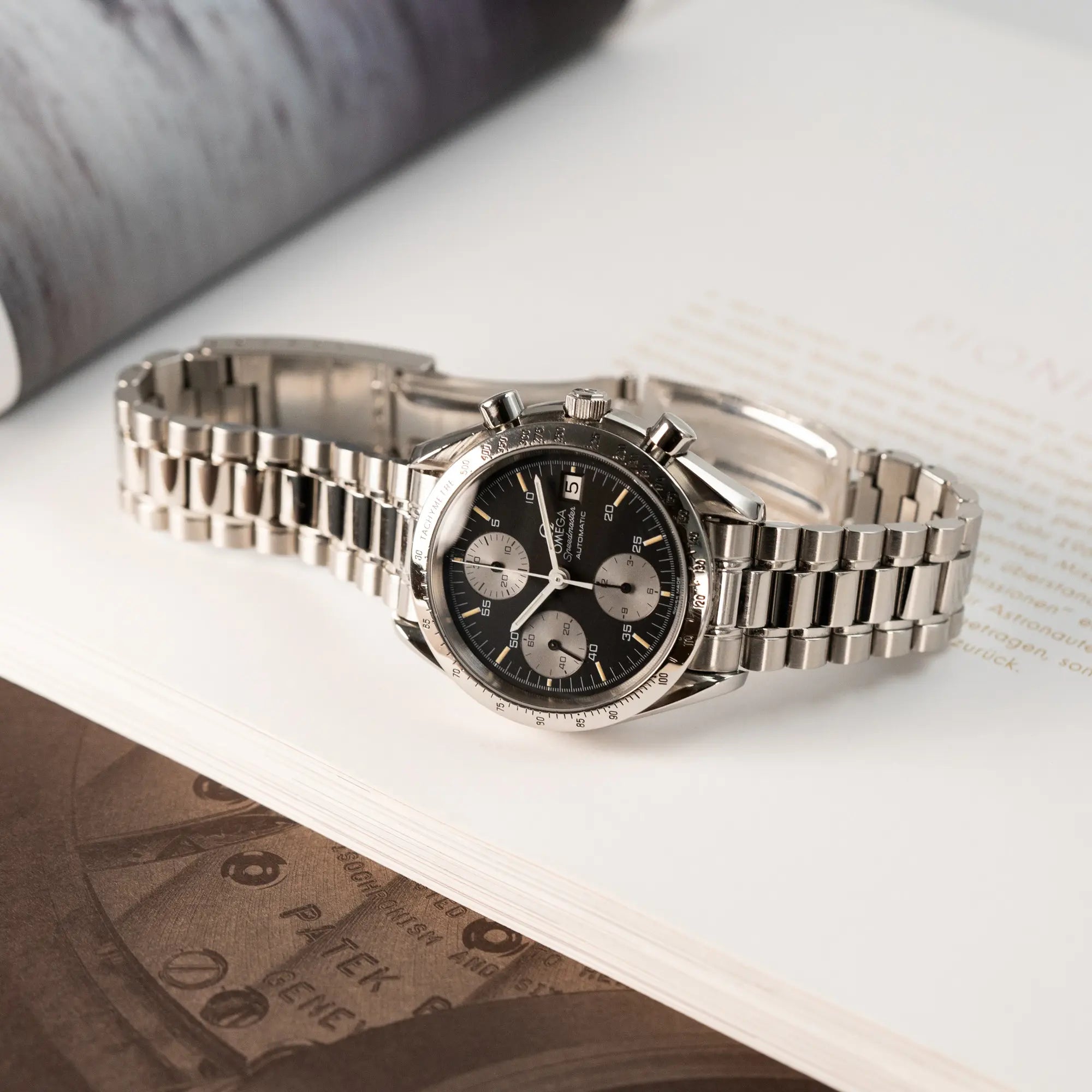 Produktfotografie der Omega Speedmaster Automatic Date mit schwarzem Zifferblatt und silbernen Totalisatoren