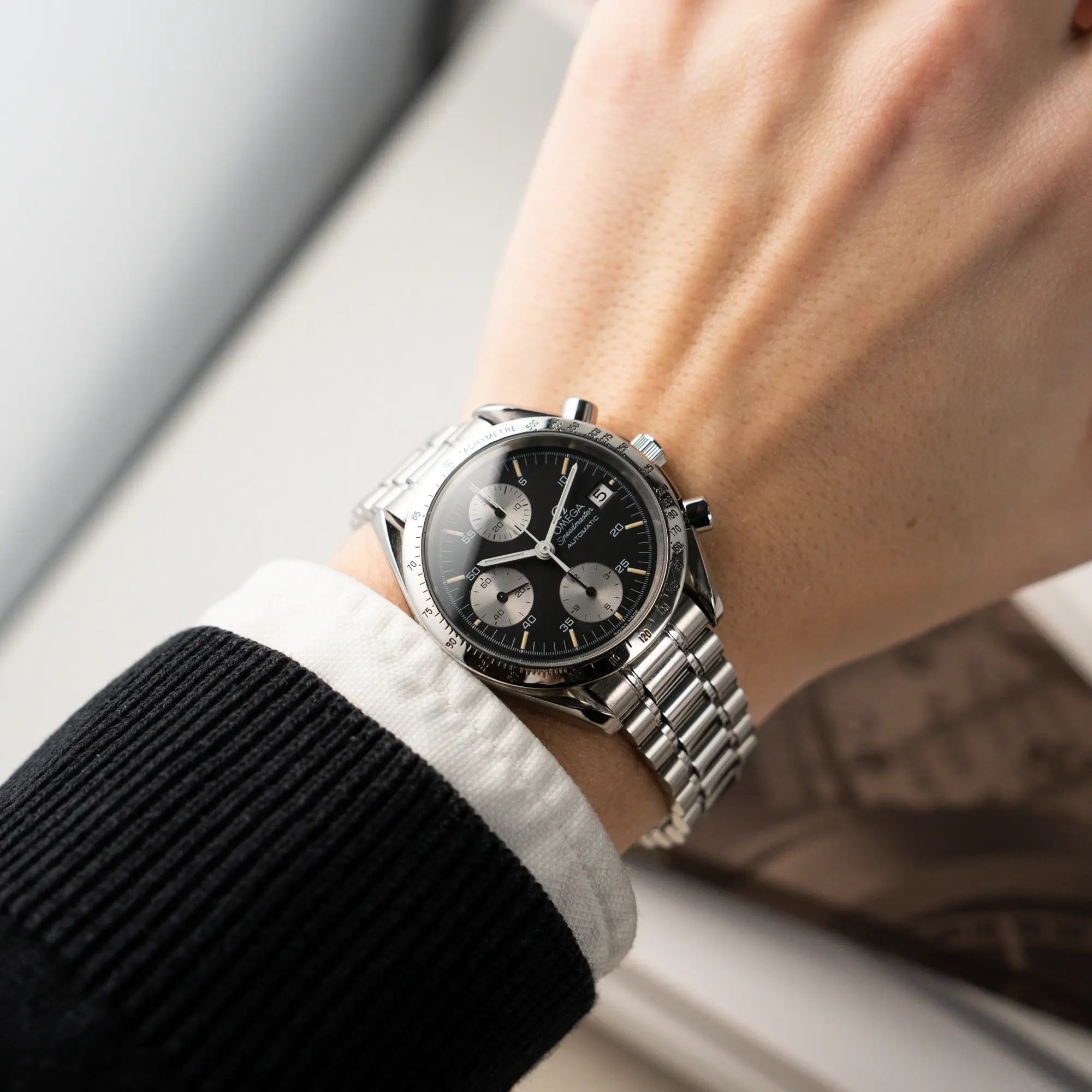 Wristshot mit der Omega Speedmaster Automatic Date mit schwarzem Zifferblatt und silbernen Totalisatoren am Edelstahl-Armband