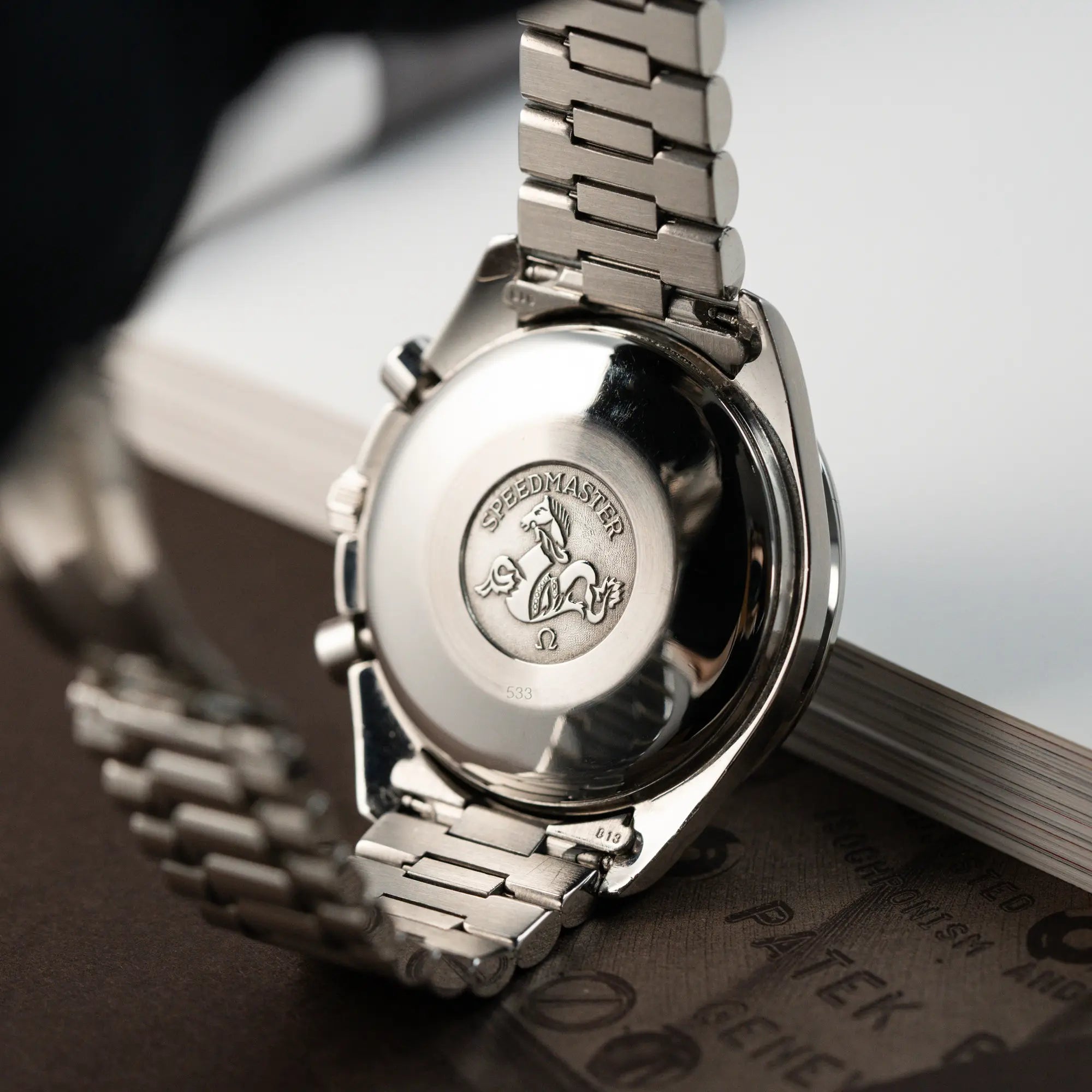 Gehäuseboden der Omega Speedmaster Automatic Date mit schwarzem Zifferblatt und silbernen Totalisatoren in Edelstahl mit "Speedmaster"-Referenz