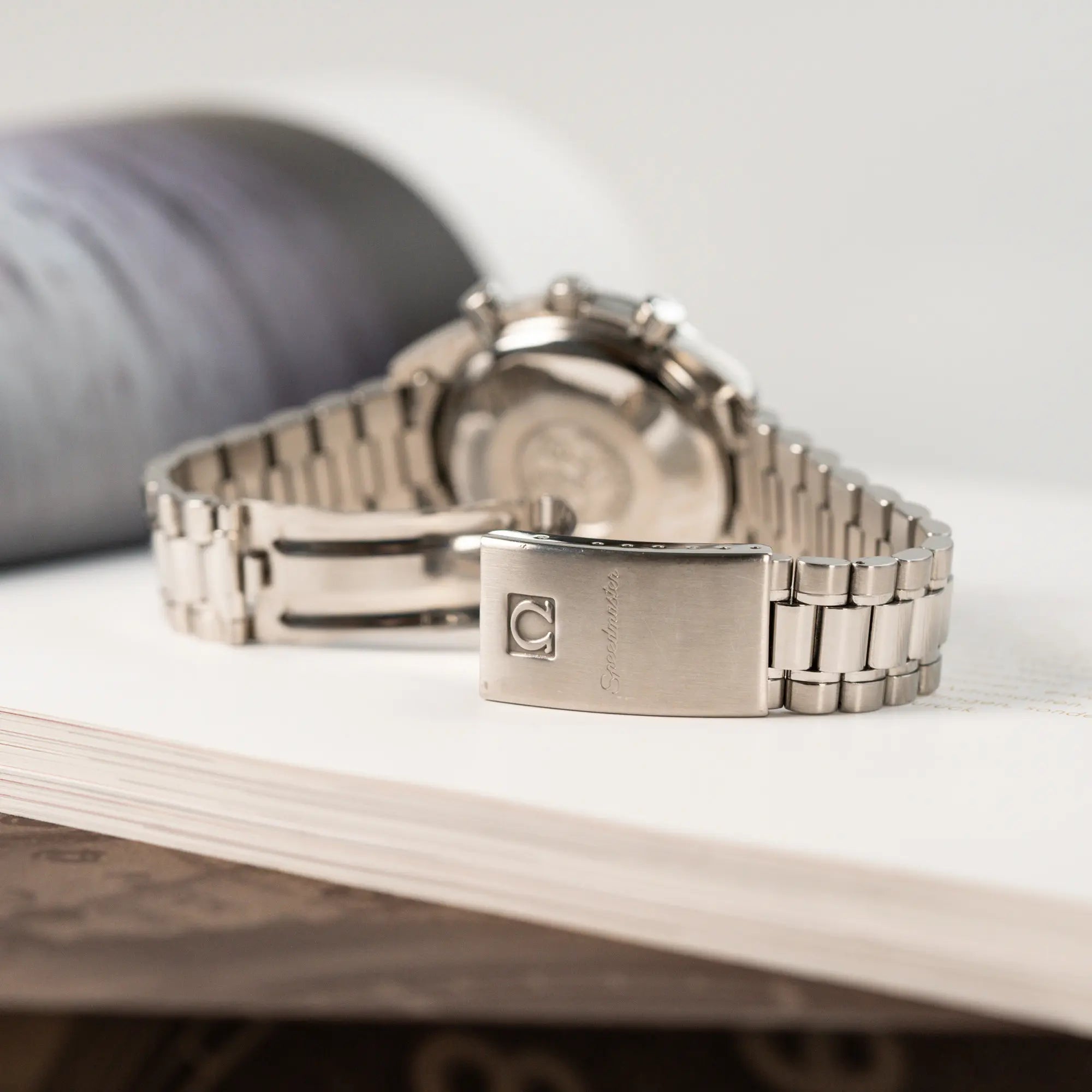 Produktfotografie der Omega Speedmaster Automatic Date mit schwarzem Zifferblatt und silbernen Totalisatoren mit Fokus auf der geöffneten Faltschliesse