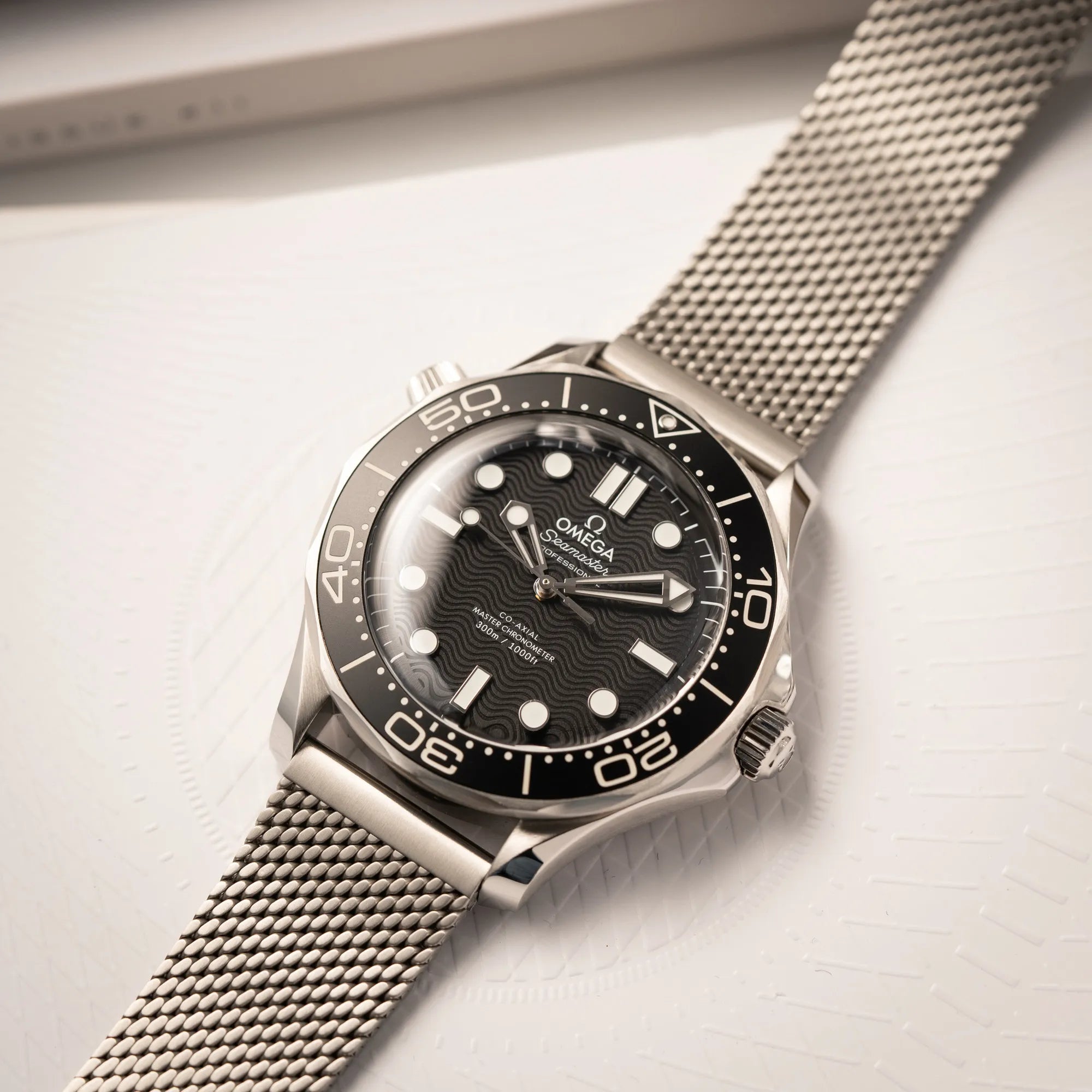 Produktfotografie als Titelbild für die Omega Seamaster 300M Diver 210.30.42.20.01.010 mit dems schwarzen Zifferblatt im Wellen-Design am Milanese-Edelstahl-Armband