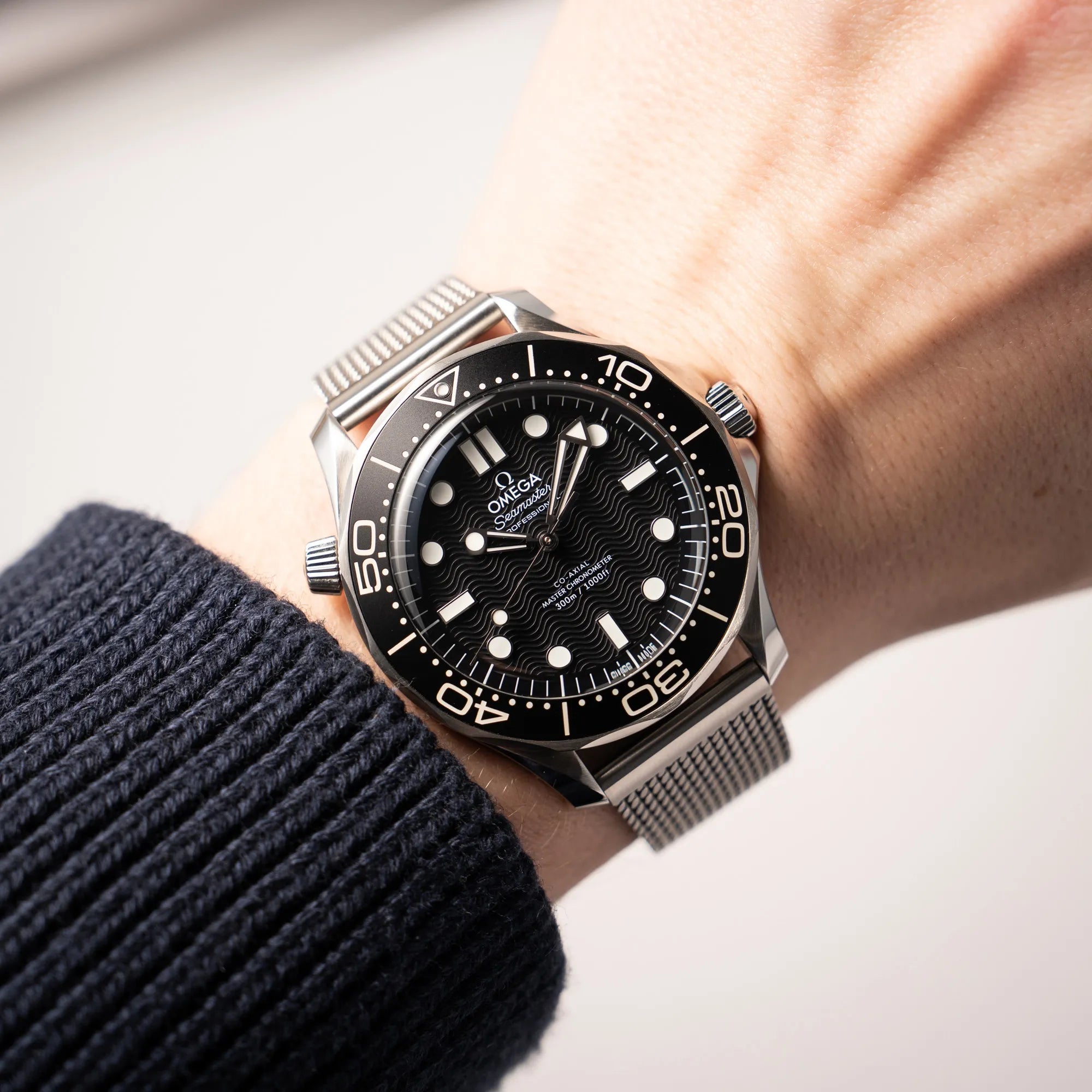 Wristshot mit der Omega Seamaster 300M Diver 210.30.42.20.01.010 mit dems schwarzen Zifferblatt im Wellen-Design am Milanese-Edelstahl-Armband