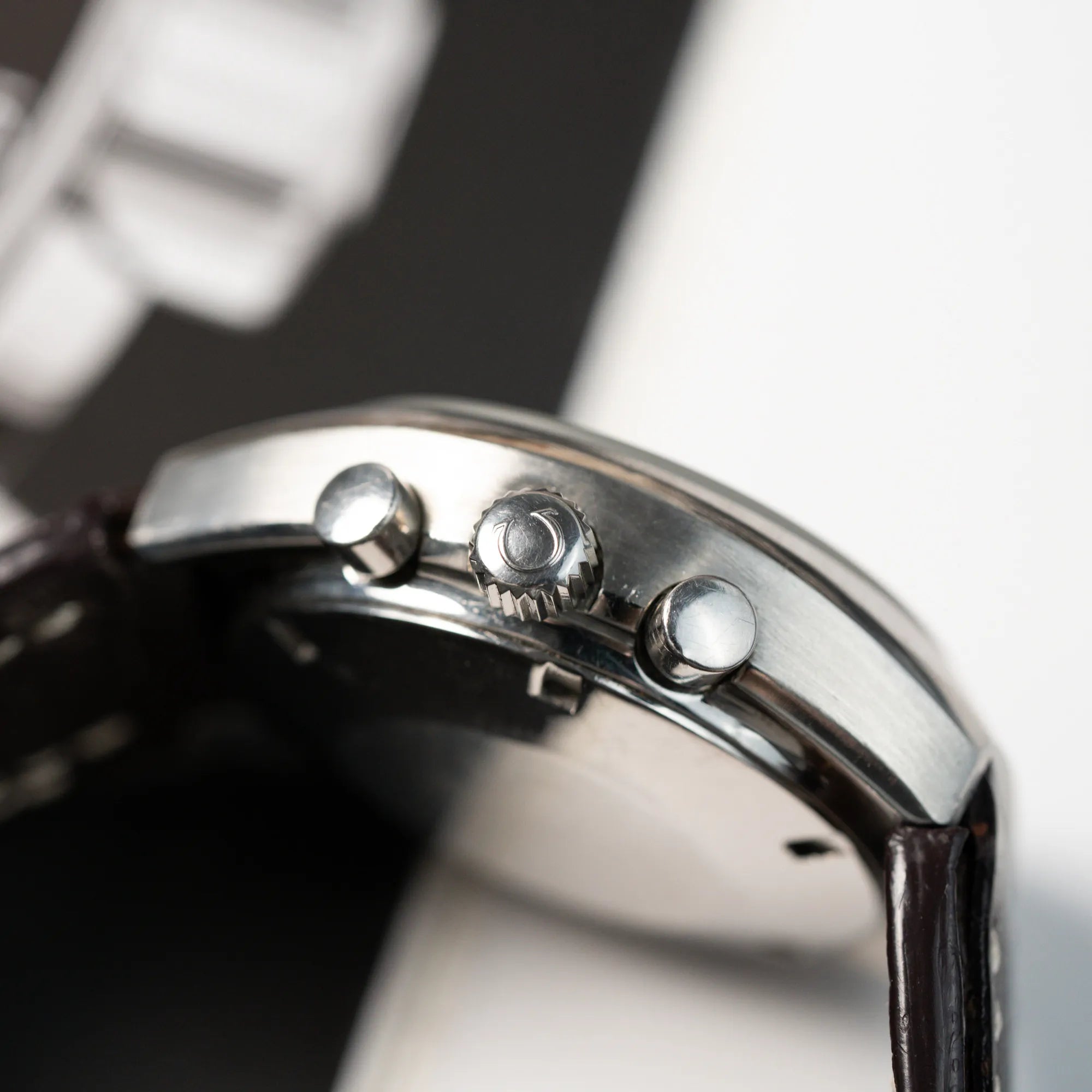 Seitliches Gehäuse mit Krone und Chronograph-Drückern der Omega Speedmaster Moonwatch Mark 2 an einem braunen Lederarmband