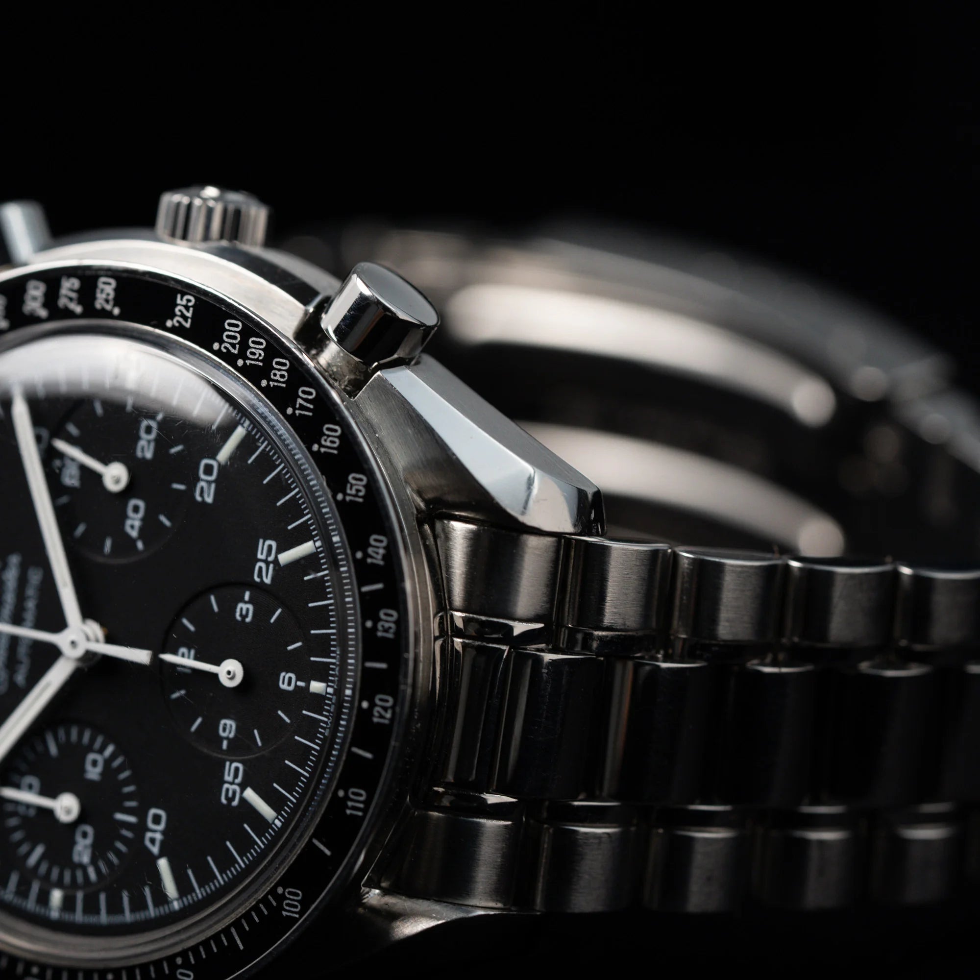 Detailaufnahme der liegenden Omega Speedmaster Reduced mit einem schwarzen Zifferblatt und weißen Indizes
