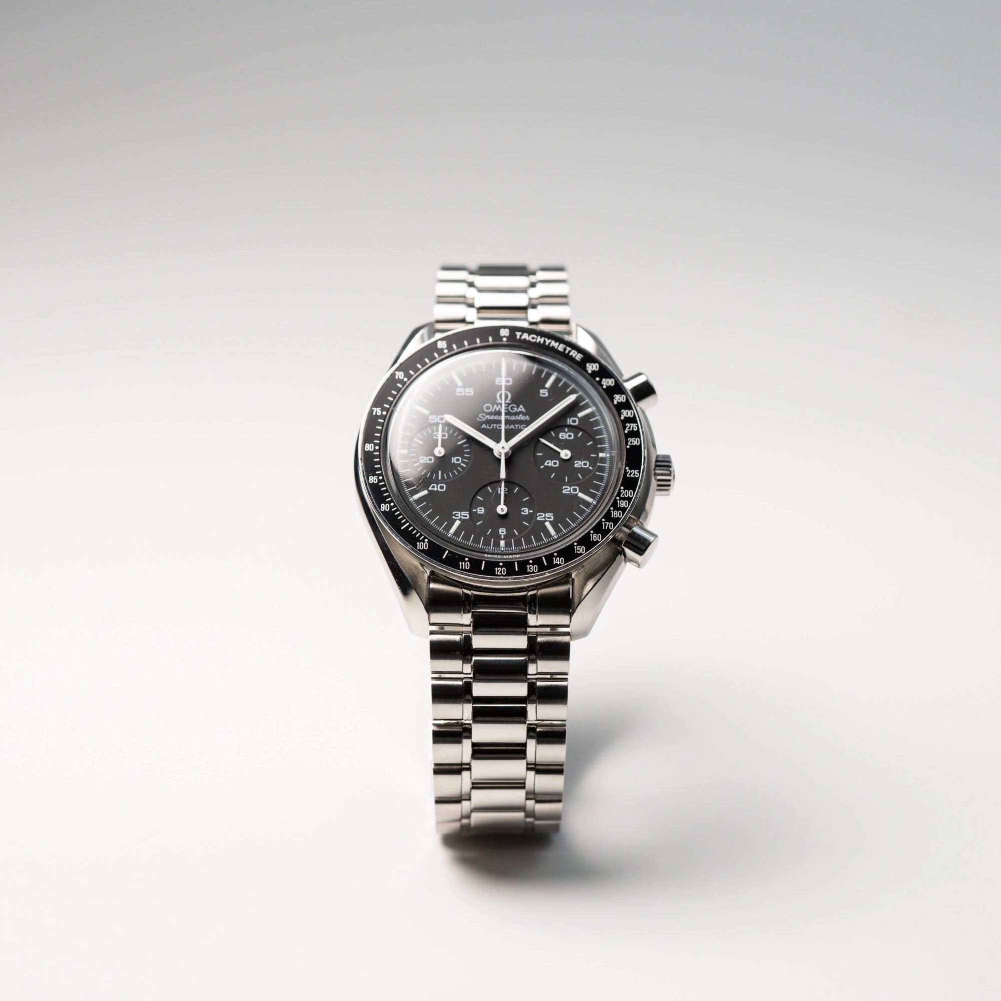 Produktfotografie der Omega Speedmaster Reduced mit einem schwarzen Zifferblatt und weißen Indizes