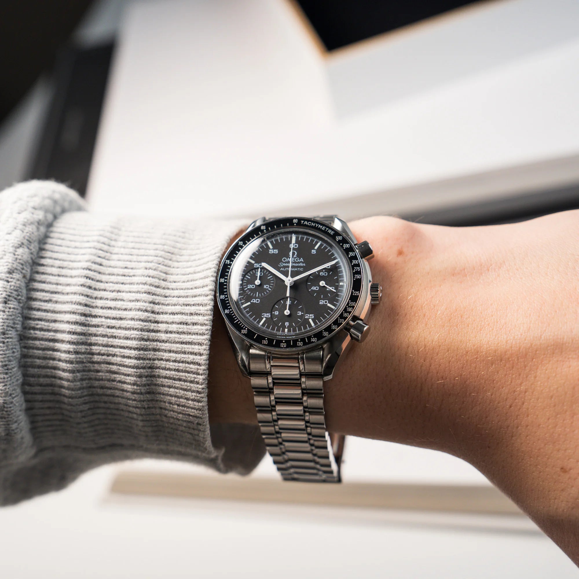 Wristshot mit der Omega Speedmaster Reduced mit schwarzen Zifferblatt und weißen Indizes - Armband im Full-Link ersichtlich