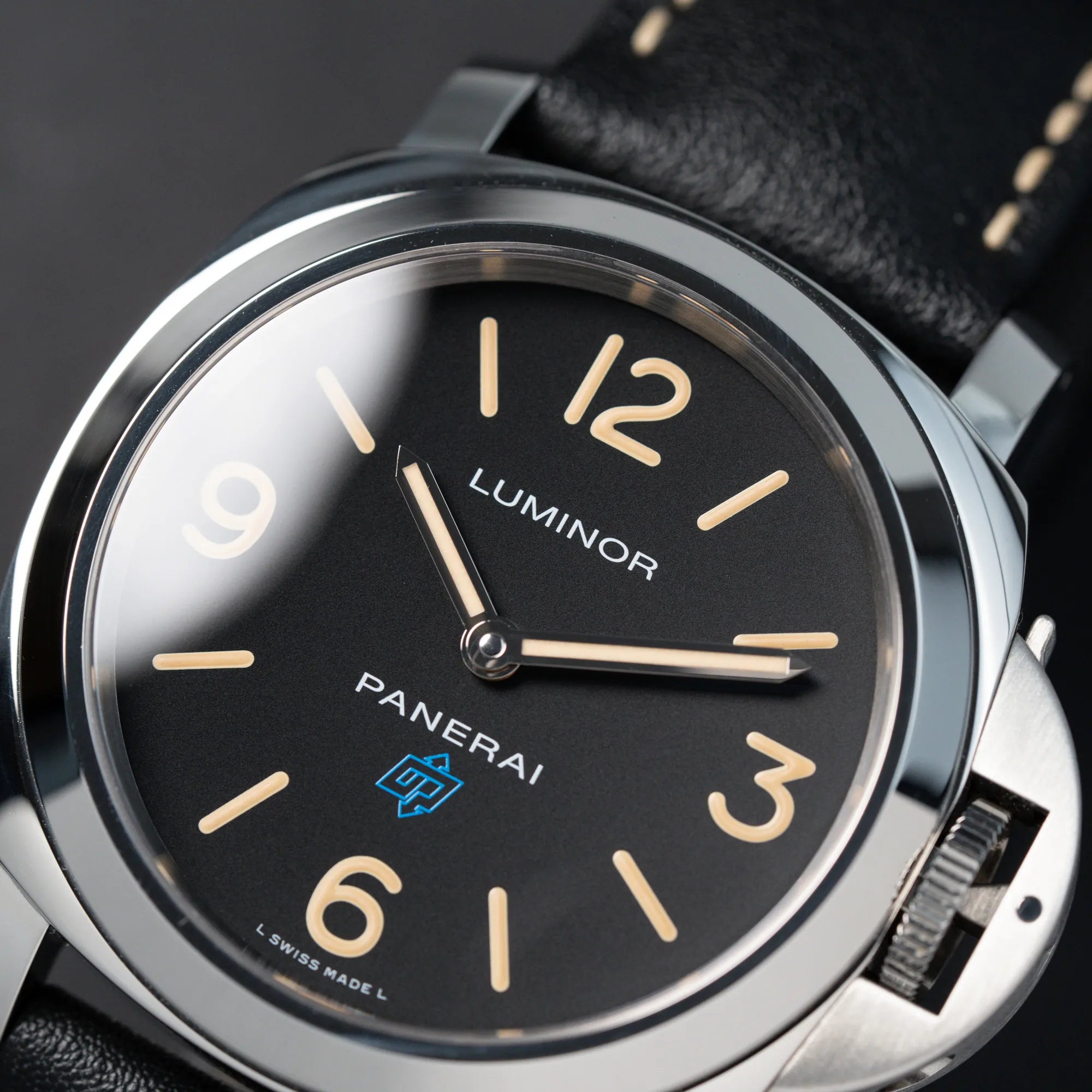 Detailaufnahme der Panerai Luminor Logo Base mit schwarzem Zifferblatt und beigen Indizes, sowie einen schwarzem Lederband