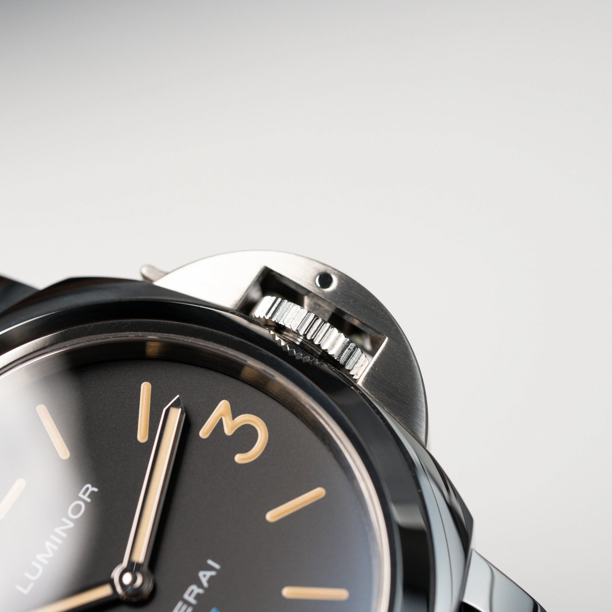 Detailaufnahme der Lünette mit Kronenschutz der Panerai Luminor Logo Base mit schwarzem Zifferblatt und beigen Indizes