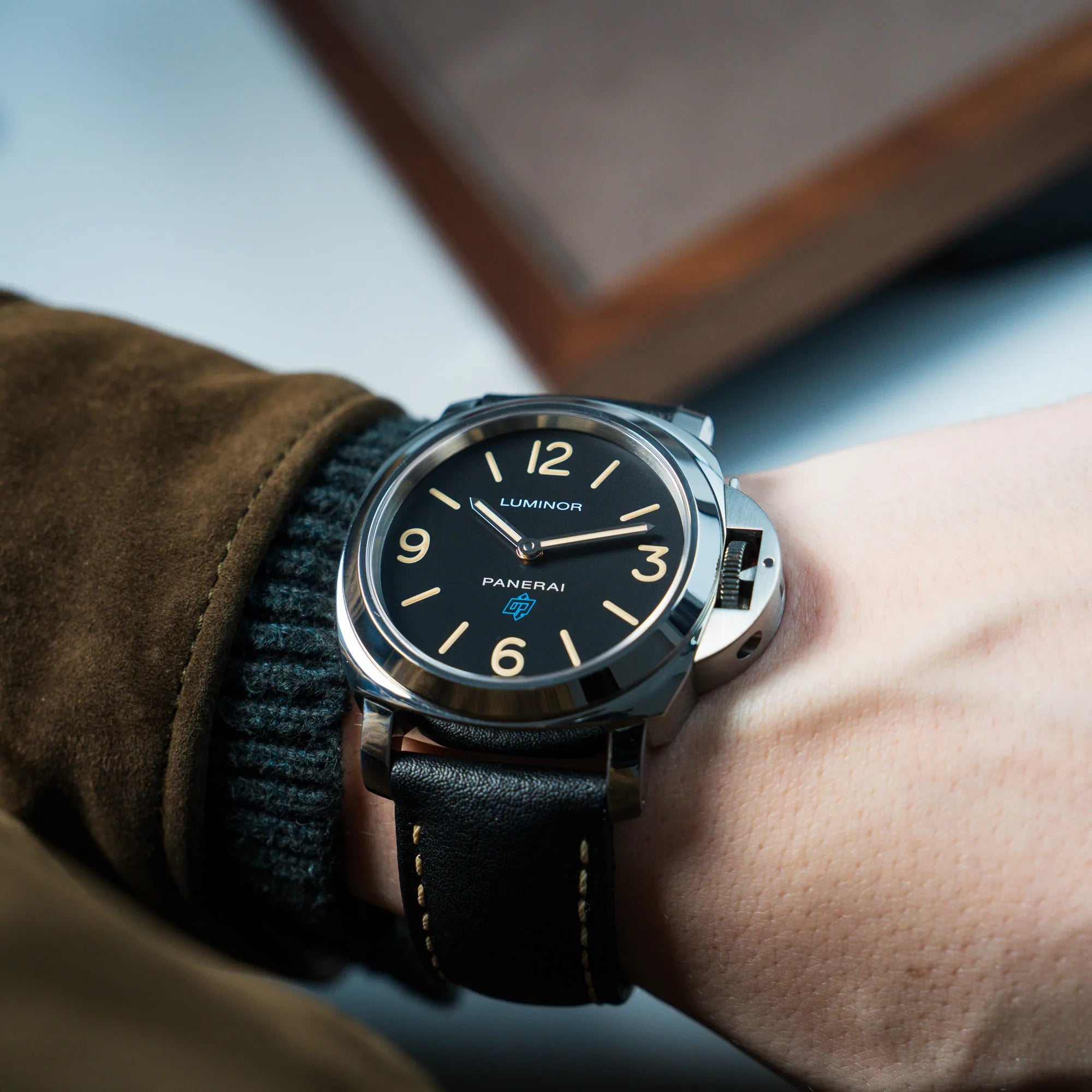Mann trägt die Panerai Luminor Logo Base mit schwarzem Zifferblatt und beigen Indizes, sowie einen schwarzem Lederband an seinem Handgelenk