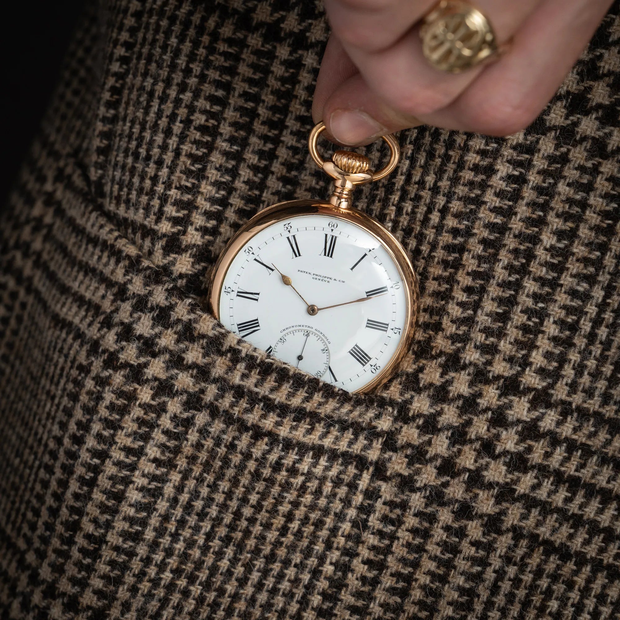 Mann zieht die Patek Philippe Gondolo Taschenuhr aus 18k Gelbgold mit weißem Zifferblatt und römischen Indizes aus seiner Jackentasche