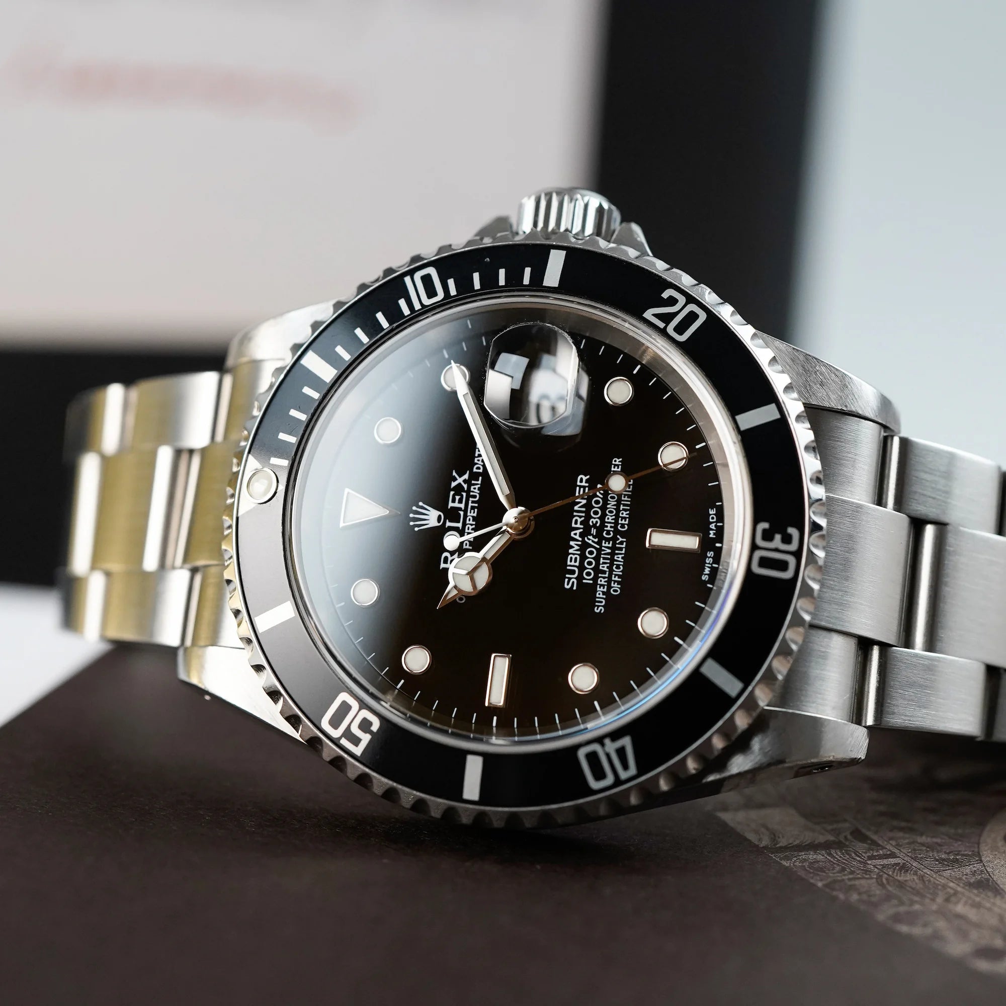 Detailaufnahme einer liegenden Rolex Submariner Date in schwarz, Referenz 16610, mit Flat-Four-Lünette