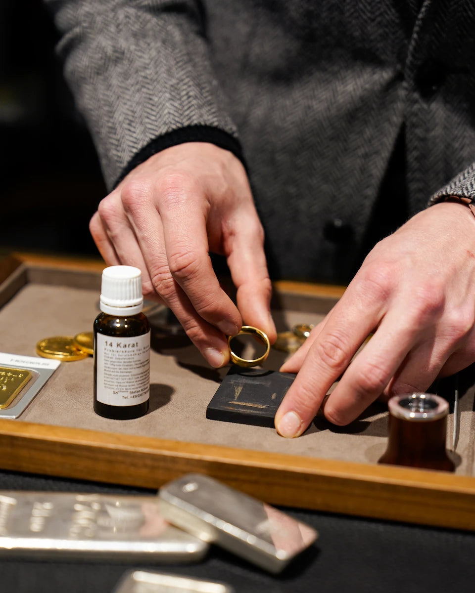 Prüfen der Legierung eines Goldrings mit einem Prüfstein und Säure während eines Altgold-Ankaufs bei Schmuckatelier Lang
