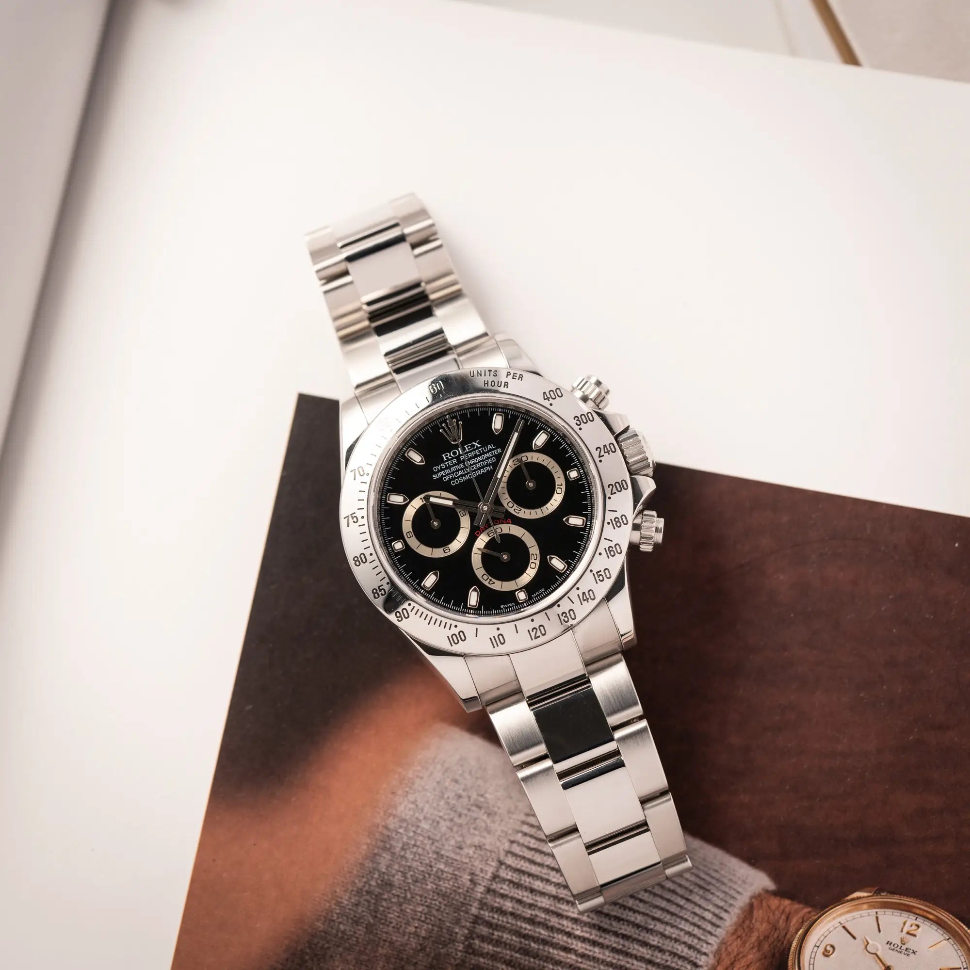 Produktfotografie als Titelbild für die Rolex Cosmograph Daytona 116520 mit schwarzem Zifferblatt und der klassischen Edelstahl-Lünette vor Umstellung auf die Keramik-Lünette