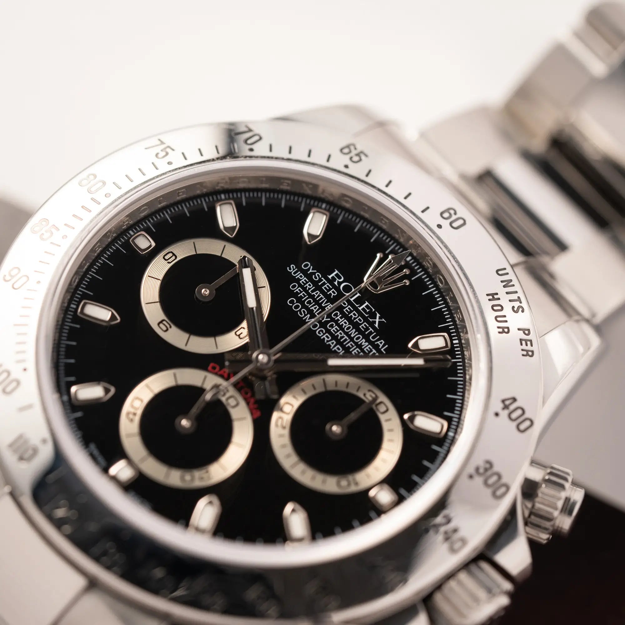 Detailaufnahme der Rolex Cosmograph Daytona 116520 mit schwarzem Zifferblatt und der klassischen Edelstahl-Lünette vor Umstellung auf die Keramik-Lünette mit Fokus auf dem Rolex Oyster Perpetual Schriftzug bei 12 Uhr auf dem Zifferblatt