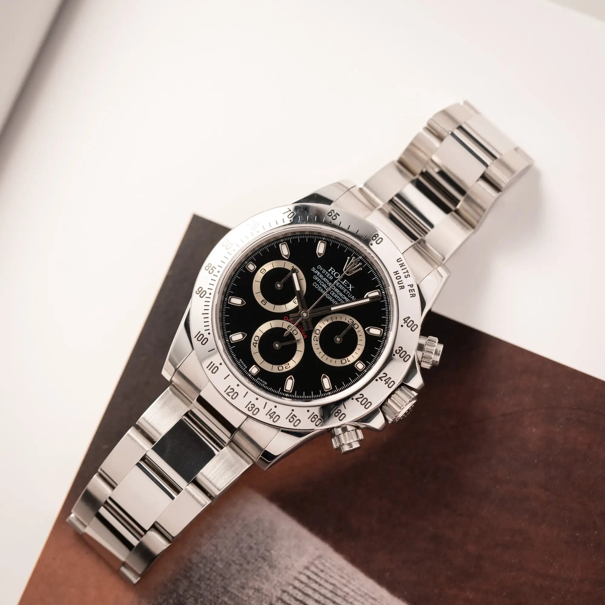 Produktfotografie der Rolex Cosmograph Daytona 116520 mit schwarzem Zifferblatt und der klassischen Edelstahl-Lünette vor Umstellung auf die Keramik-Lünette