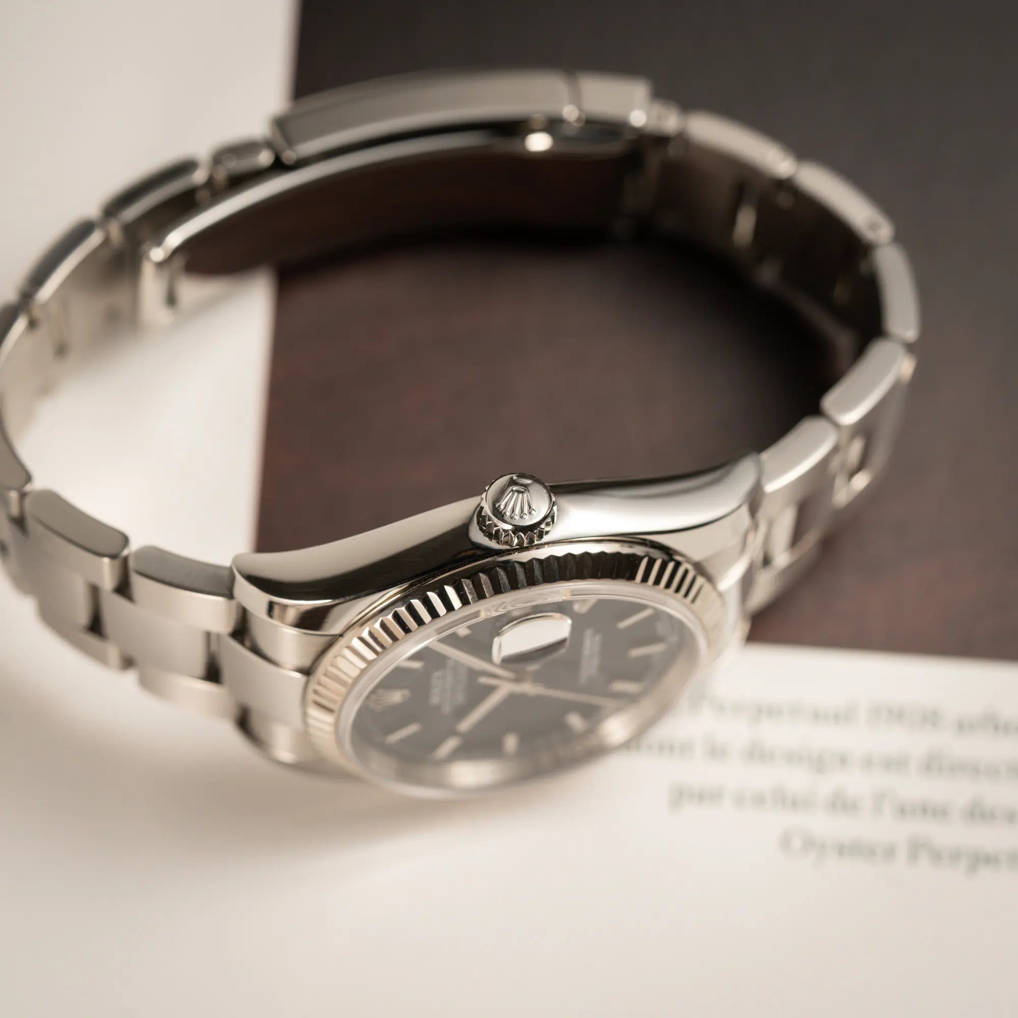 Produktfotografie der Rolex Datejust 36 der Referenz 116234 mit geriffelter Lünette und blauem Sonnenschliff-Zifferblatt mit Fokus auf der Aufzugskrone an der seitlichen Gehäuseflanke