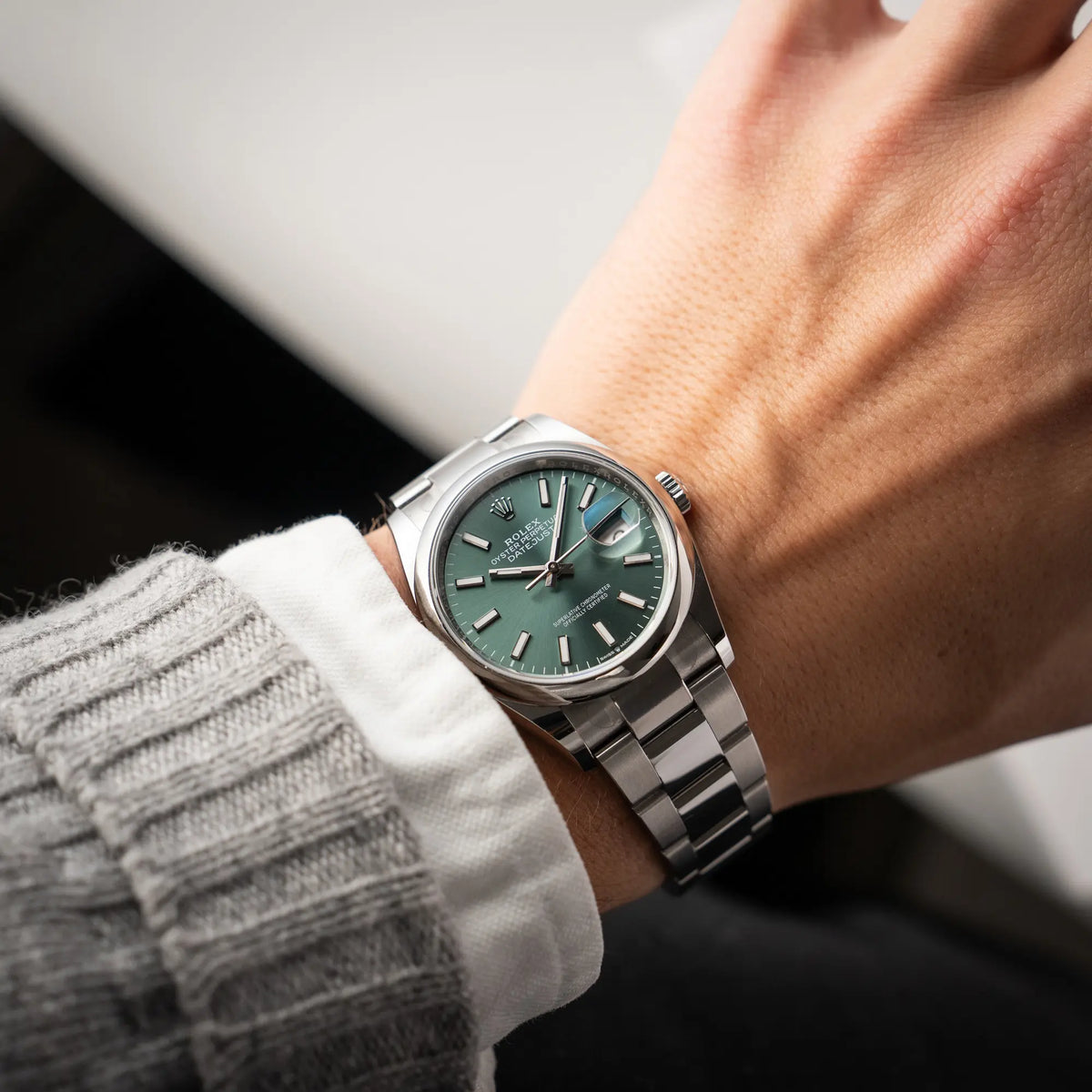 Mann trägt die mit Stickern teil-verklebte Rolex Datejust 36 der Referenz 126200 mit glatter Lünette am Oyster-Stahlband mit dem Mint-Green-Zifferblatt an seinem Handgelenk