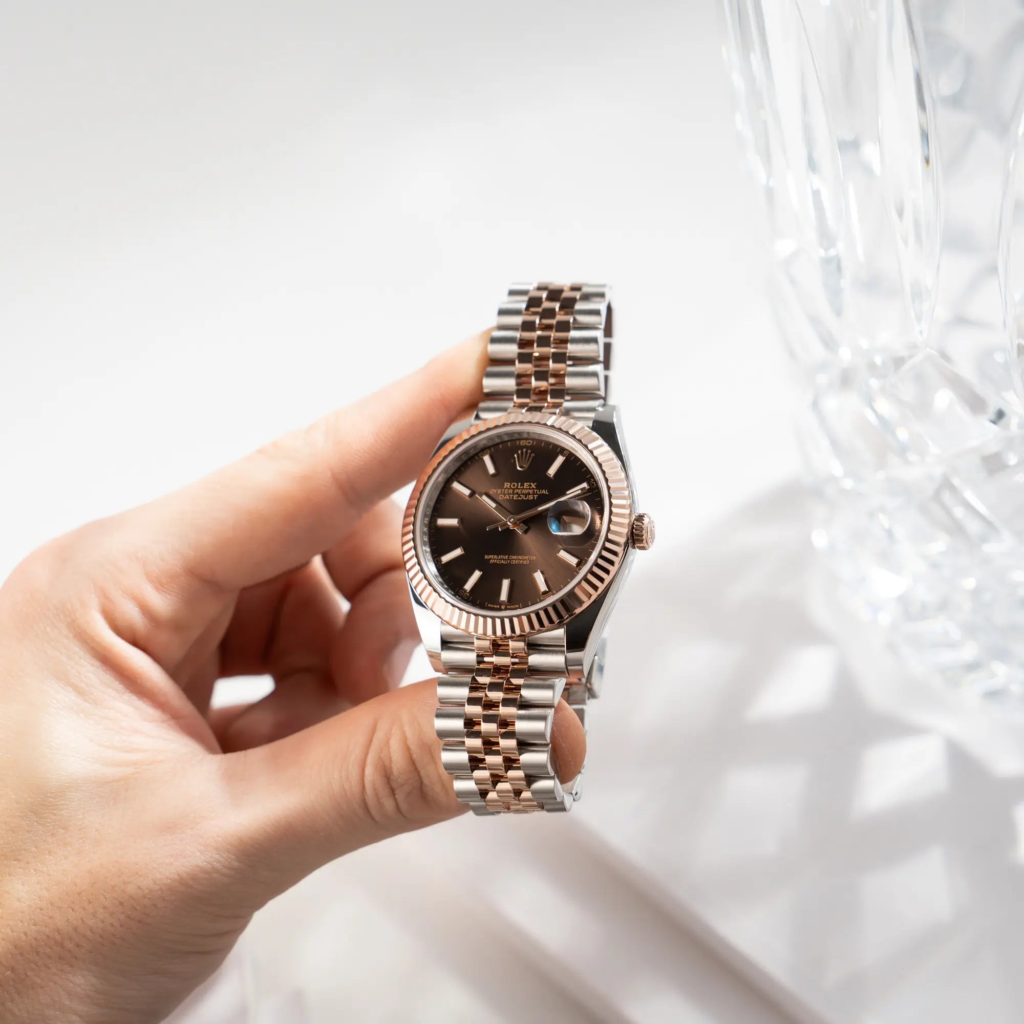 Mann hält die bicolor Rolex Datejust 41 der Referenz 126331 Chocolate in Stahl-Roségold mit einem zum Roségold passenden braunen Zifferblatt am zugehörigen Jubilee-Armband in seiner Hand und präsentiert die Uhr in die Kamera