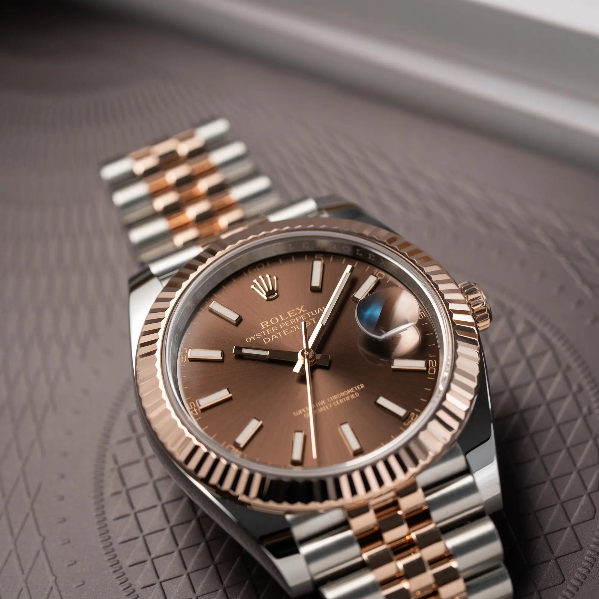 Detailaufnahme der flach liegenden bicolor Rolex Datejust 41 der Referenz 126331 Chocolate in Stahl-Roségold mit einem zum Roségold passenden braunen Zifferblatt am zugehörigen Jubilee-Armband