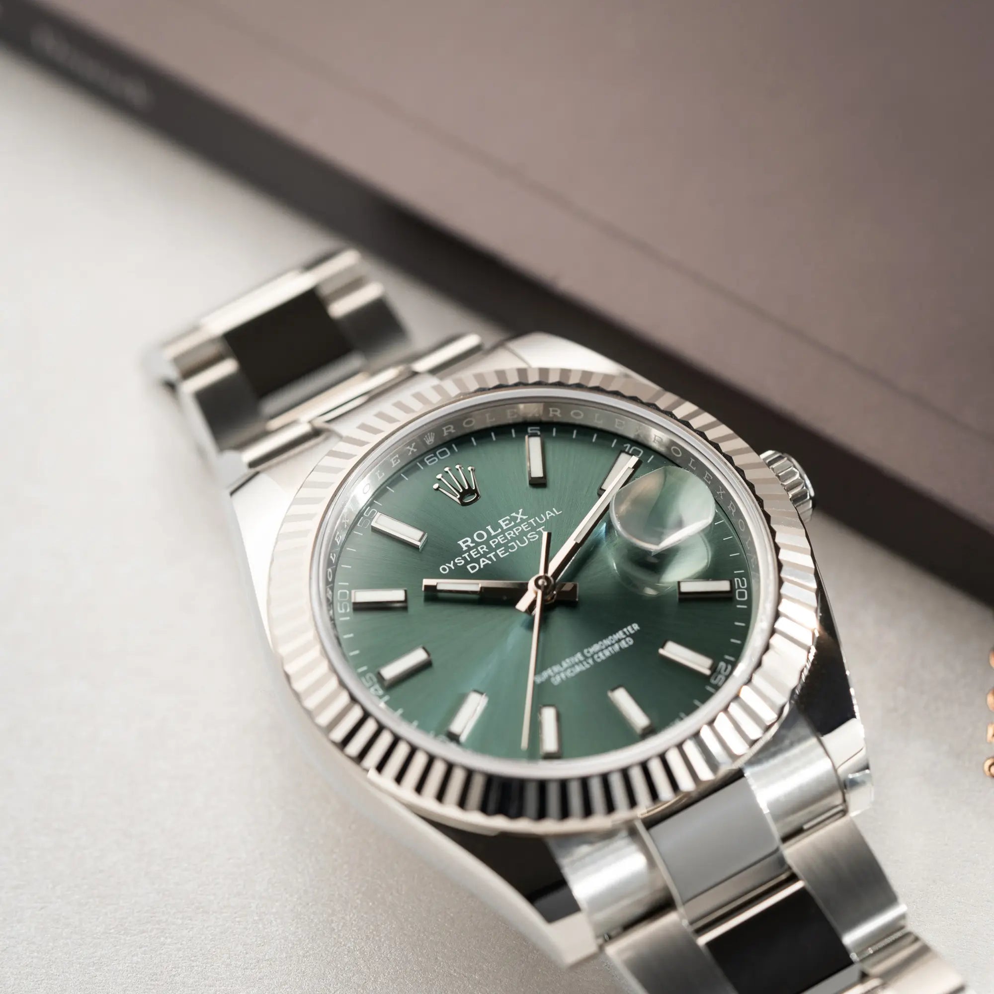 Produktfotografie der Rolex Datejust 41 der Referenz 126334 mit dem grünem Zifferblatt am Oyster-Stahlband mit Fokus auf der geriffelten Lünette
