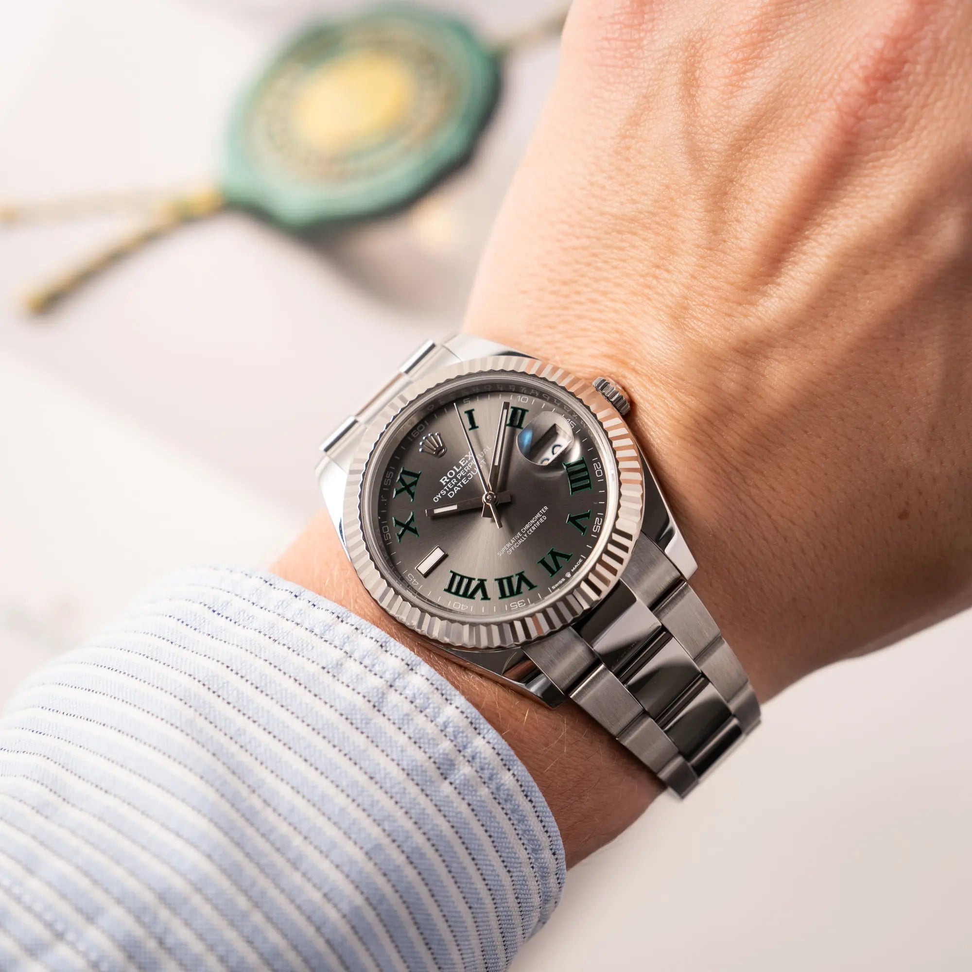 Mann trägt die Rolex Datejust 41 der Referenz 126334 mit geriffelter Weißgold-Lünette und Oyster-Stahlband mit dem grauen Wimbledon-Zifferblatt mit schwarz-grünen Indizes für einen Wristshot an seinem Handgelenk