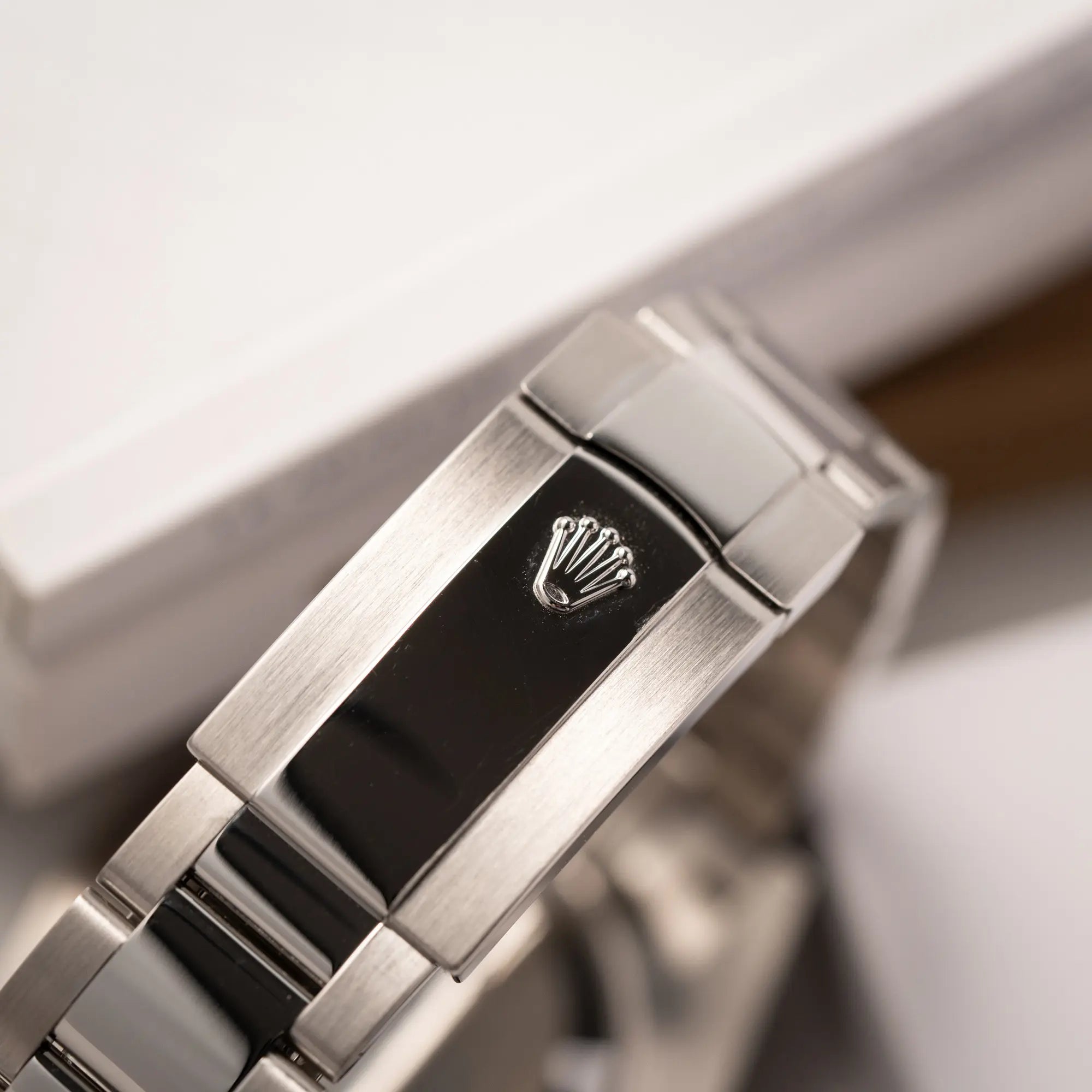 Produktfotografie zeigt die geschlossene Oyster-Schliesse der Rolex Datejust 41 der Referenz 126334 mit geriffelter Weißgold-Lünette und Oyster-Stahlband mit dem grauen Wimbledon-Zifferblatt mit schwarz-grünen Indizes